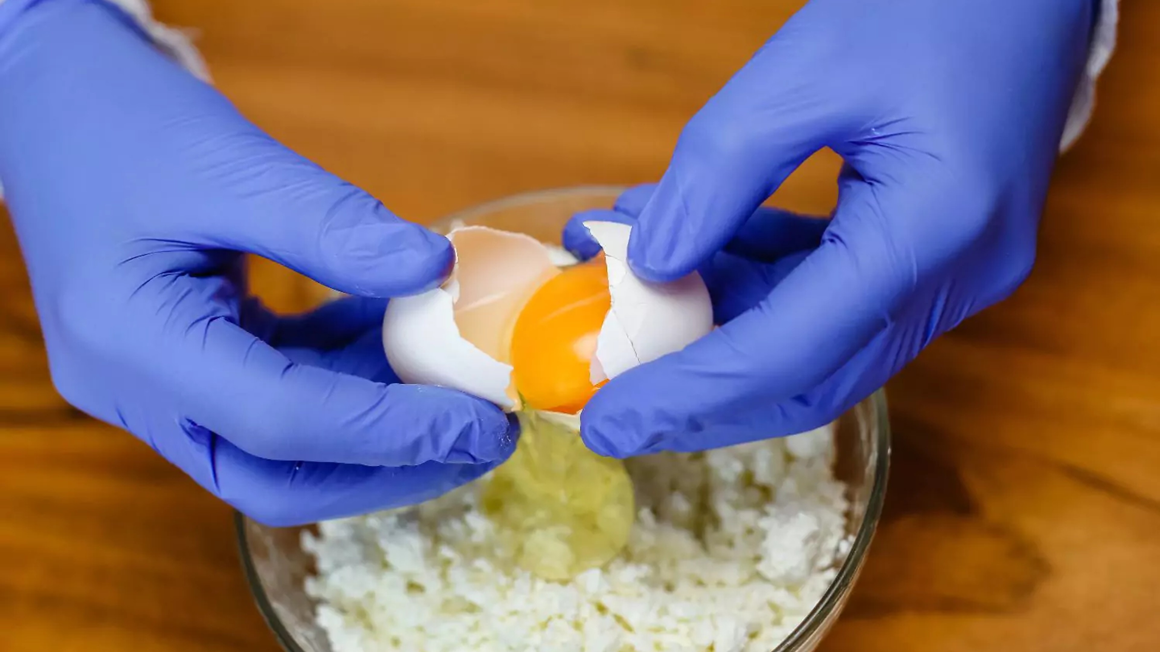 Nitrile Gloves being used to crack eggs into a bowl for cooking preparation