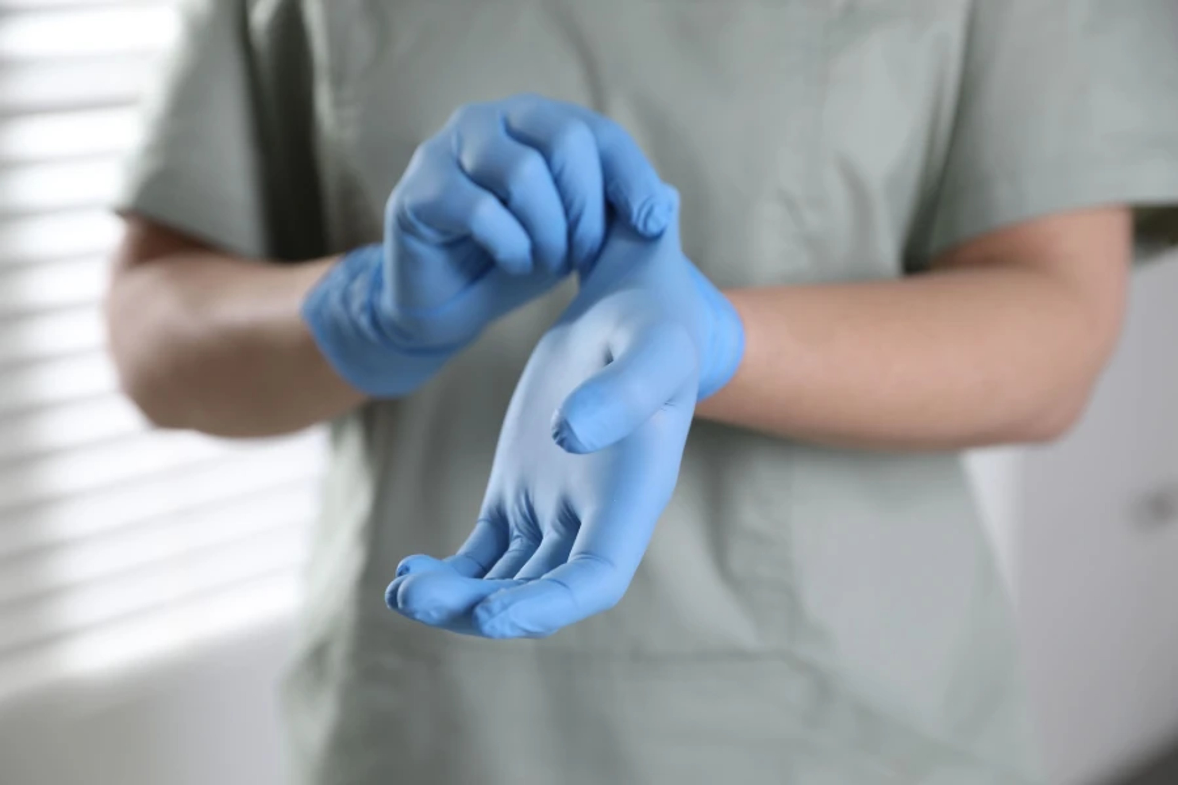 INTCO gloves being put on by a healthcare professional in a clinical setting
