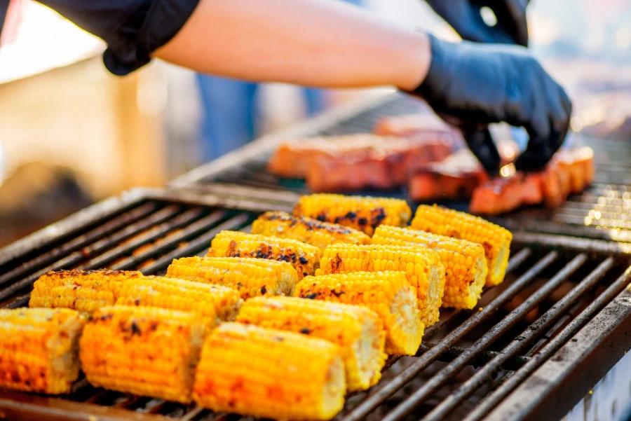 Grilled Corn on the Cob with Nitrile Gloves Handling Steaks at BBQ Party