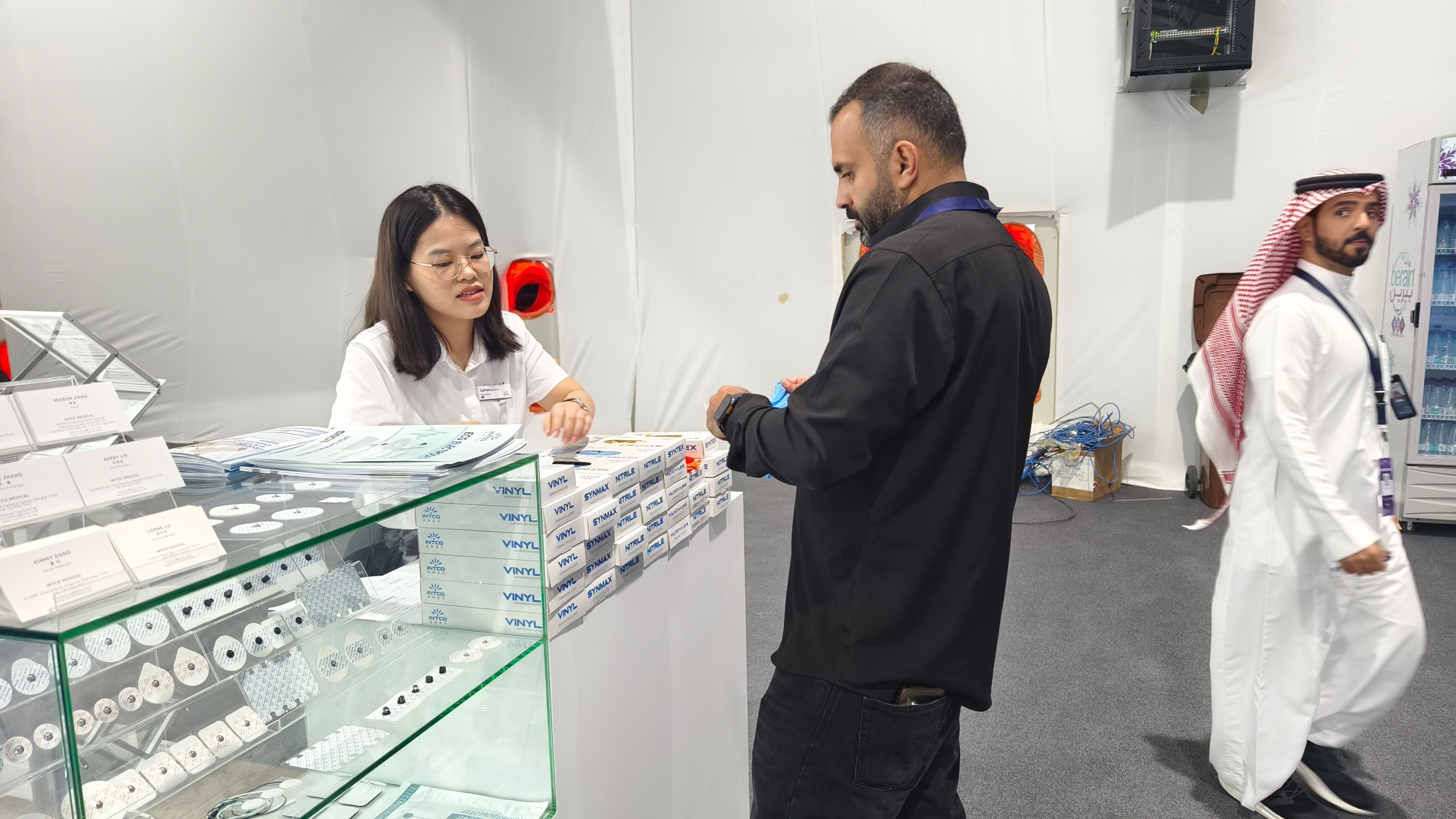 Visitor discussing INTCO Medical glove products at the exhibition stand