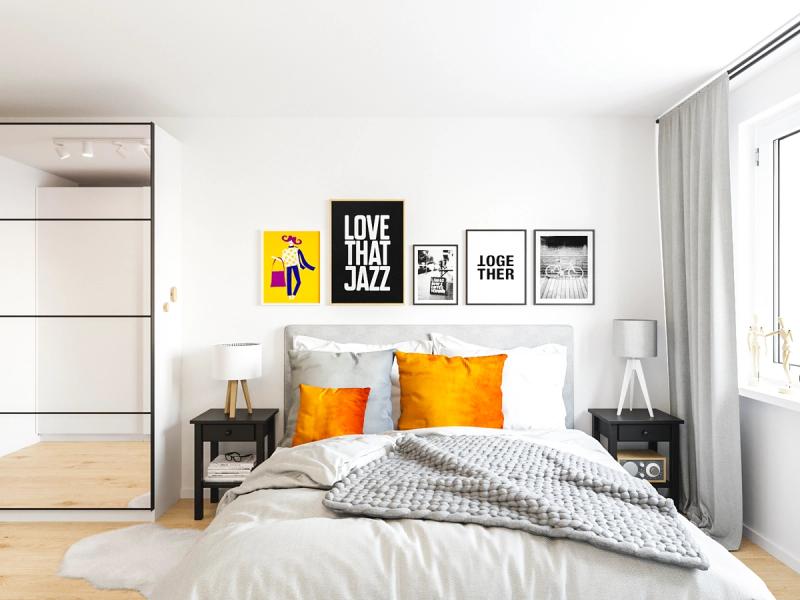 Łóżko 180x200 przy długiej ścianie. Pomarańczowe poduszki i grafiki — jedyne mocne akcenty w jasnym wnętrzu.