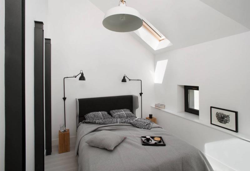 Sypialnia na poddaszu w mieszkaniu 35 m² w Krakowie. Układ dopasowany do kształtu pokoju — łóżko przy najwyższej ścianie, okno połaciowe nad nim.