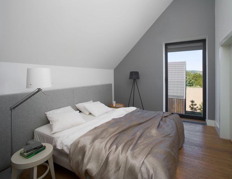 Ścianka kolankowa ma tu 160 cm — wystarczająco, żeby zagłówek miał pełną wysokość a wnętrze było w pełni komunikacyjne mimo skosów. Sypialnia w domu pod Krakowem.