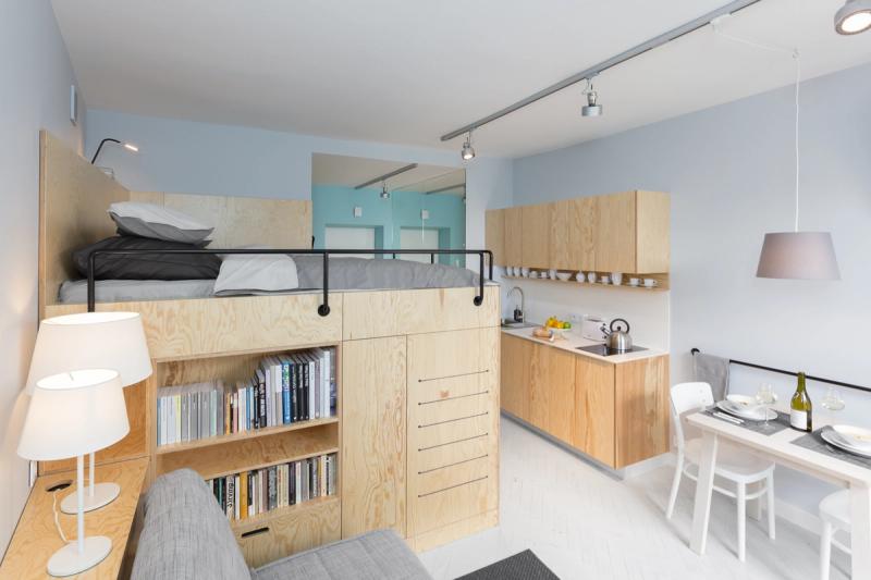 Antresola od strony salonu. Łóżko 180×200 na górze, regał na książki pod spodem, sofa i stolik kawowy na parterze.