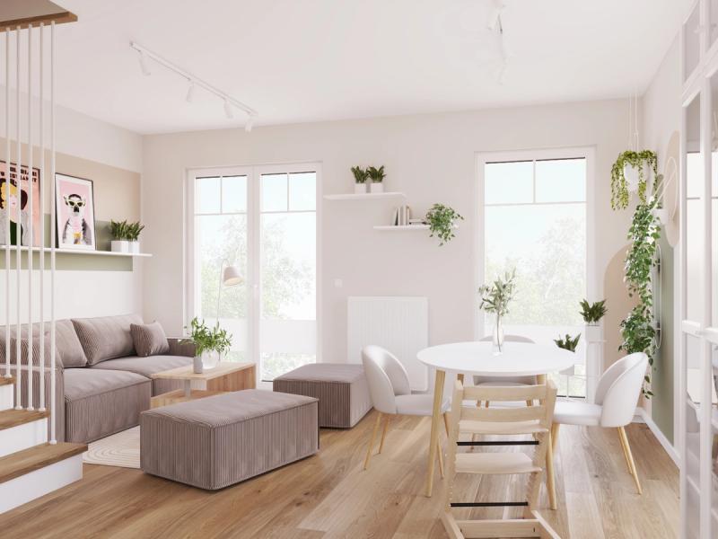 Okrągły stół na drewnianych nogach, Tripp Trapp obok. Sofa modułowa sztruksowa z dwoma pufami — razem osiem miejsc, bez dostawiania krzeseł z kuchni.