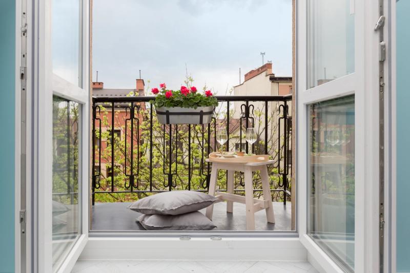 Balkon. Dodatkowy metr kwadratowy, ale poczucie przestrzeni o wiele większe. Taboret, poduszka, wino — pełna lista wyposażenia.