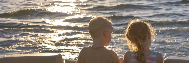 Two children watching the sunset aboard a pontoon