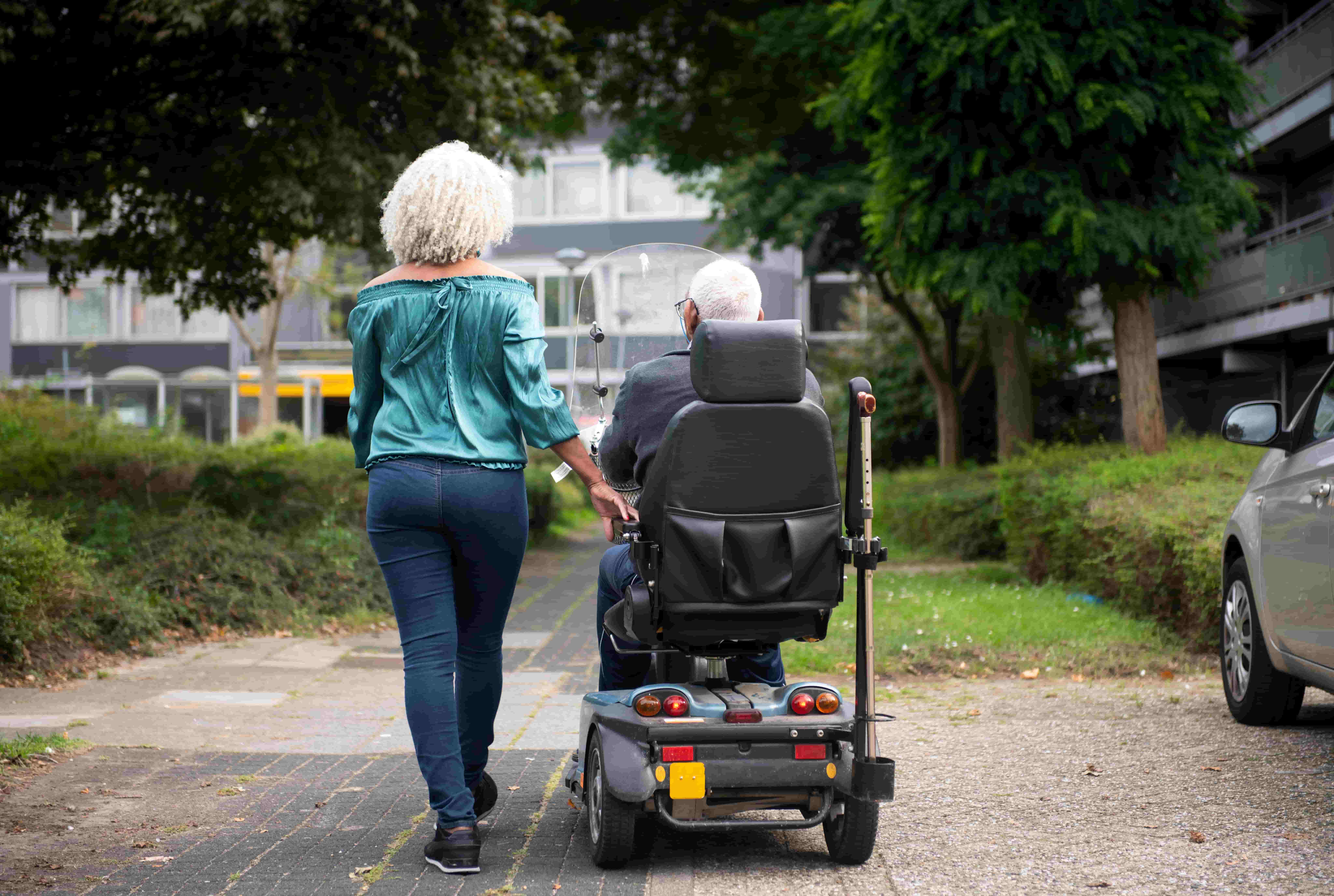 Two people next to each other, one in an electric wheelchair