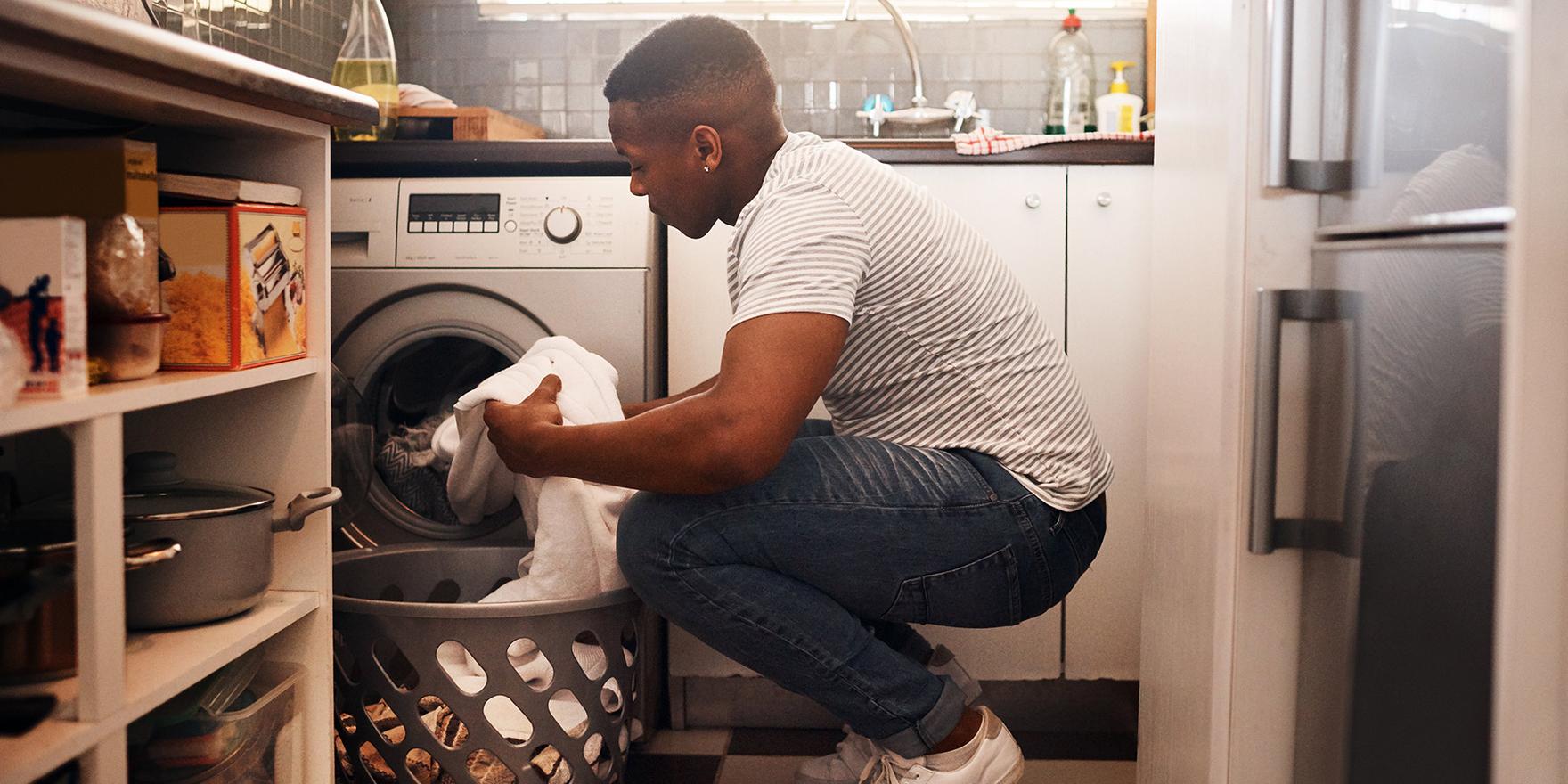 Person kneeling next to laundry machine