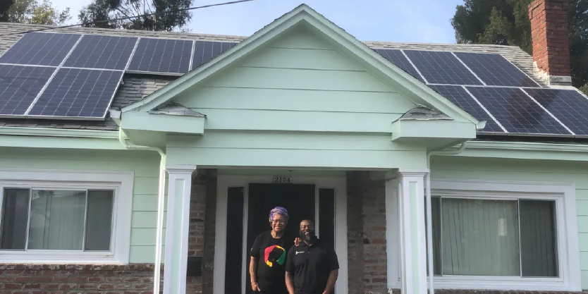 Oakland resident Cheryl Ajirotutu with Mark Hall, CEO of Revalue.io, after putting solar panels on her roof.