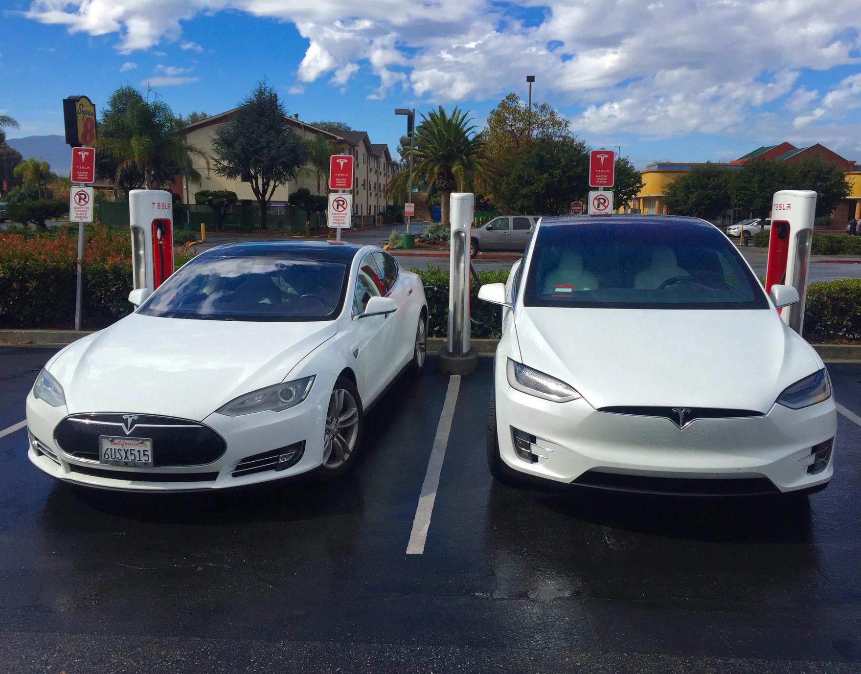 Two white Teslas charging next to each other