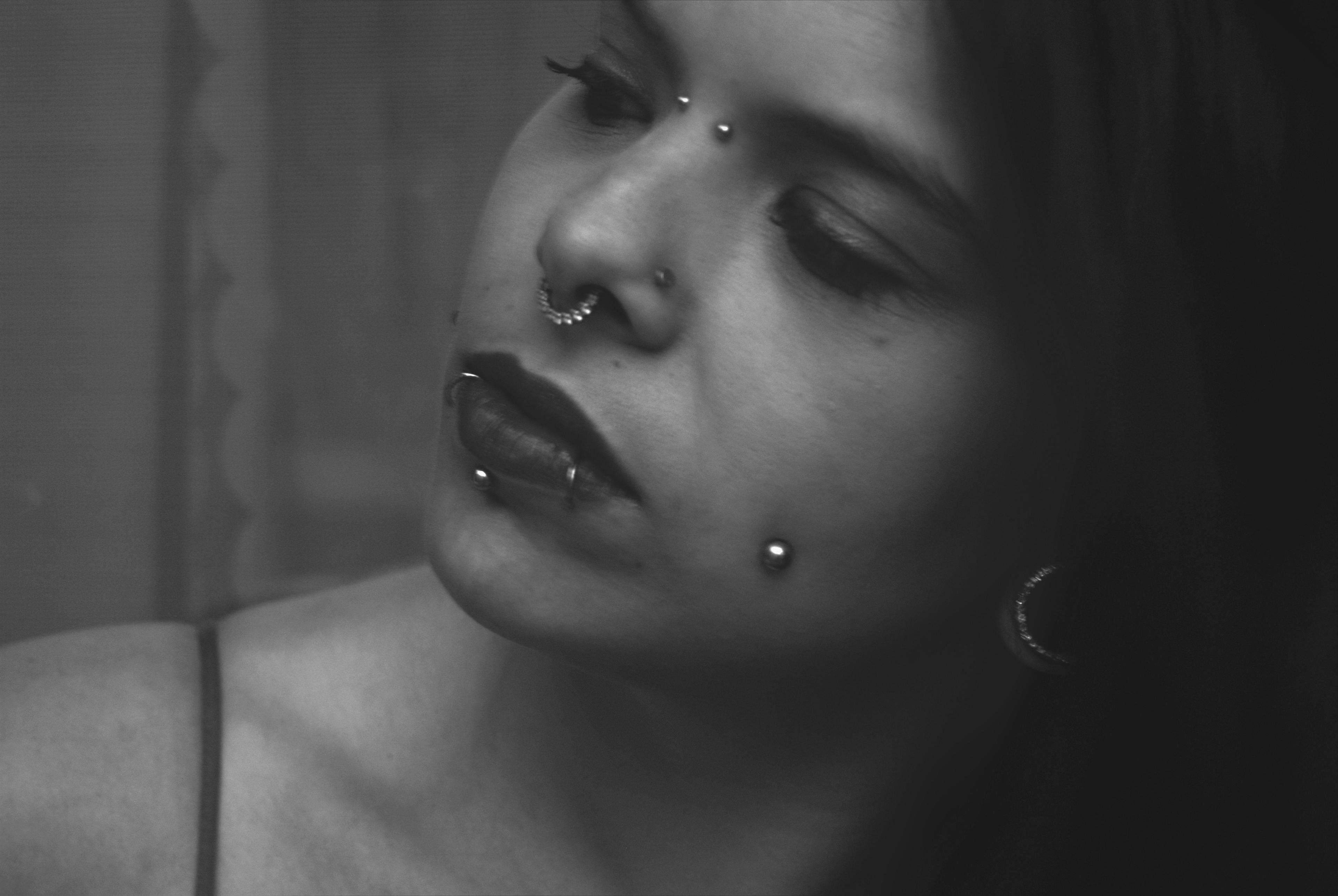 Black-and-white portrait of a client with septum and lip piercings