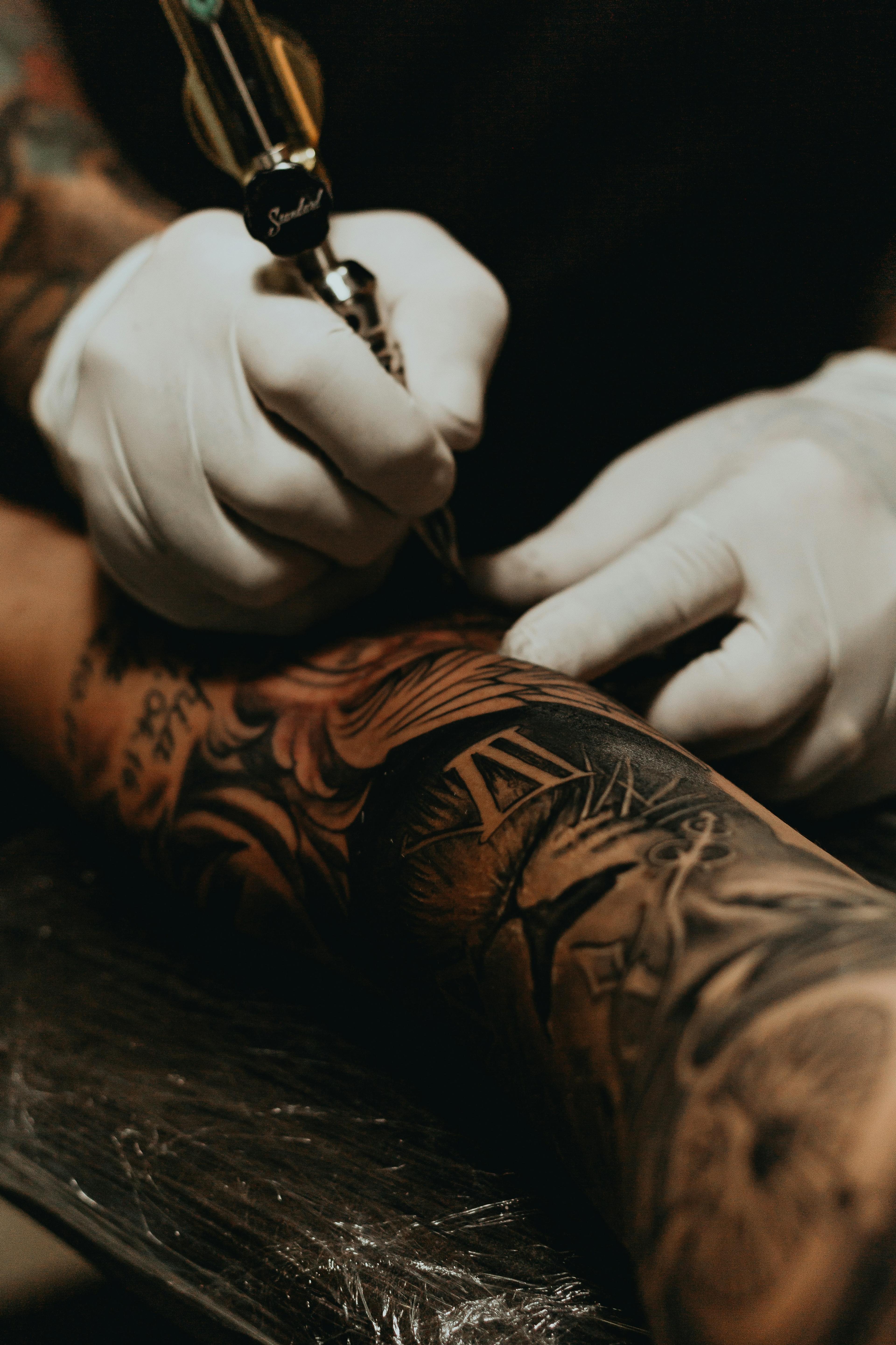 Close-up of a detailed black-and-grey sleeve being tattooed