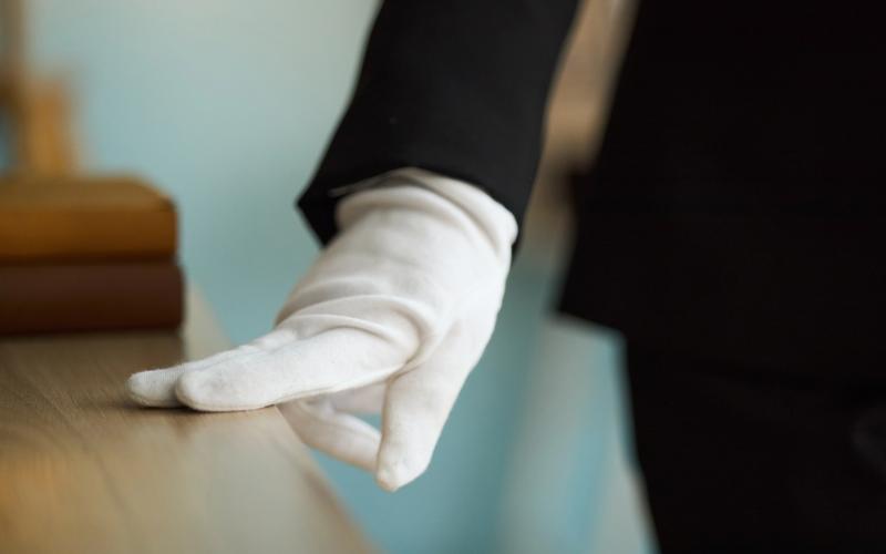 White glove service — attendant wearing white gloves resting hand on polished surface, representing precision and care by Cadiz & Lluis