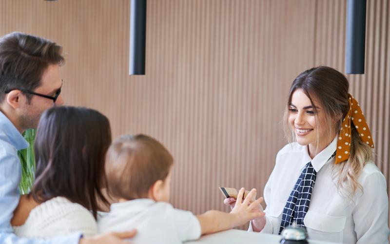 A concierge behind a reception desk handing a key card to a couple with a young child