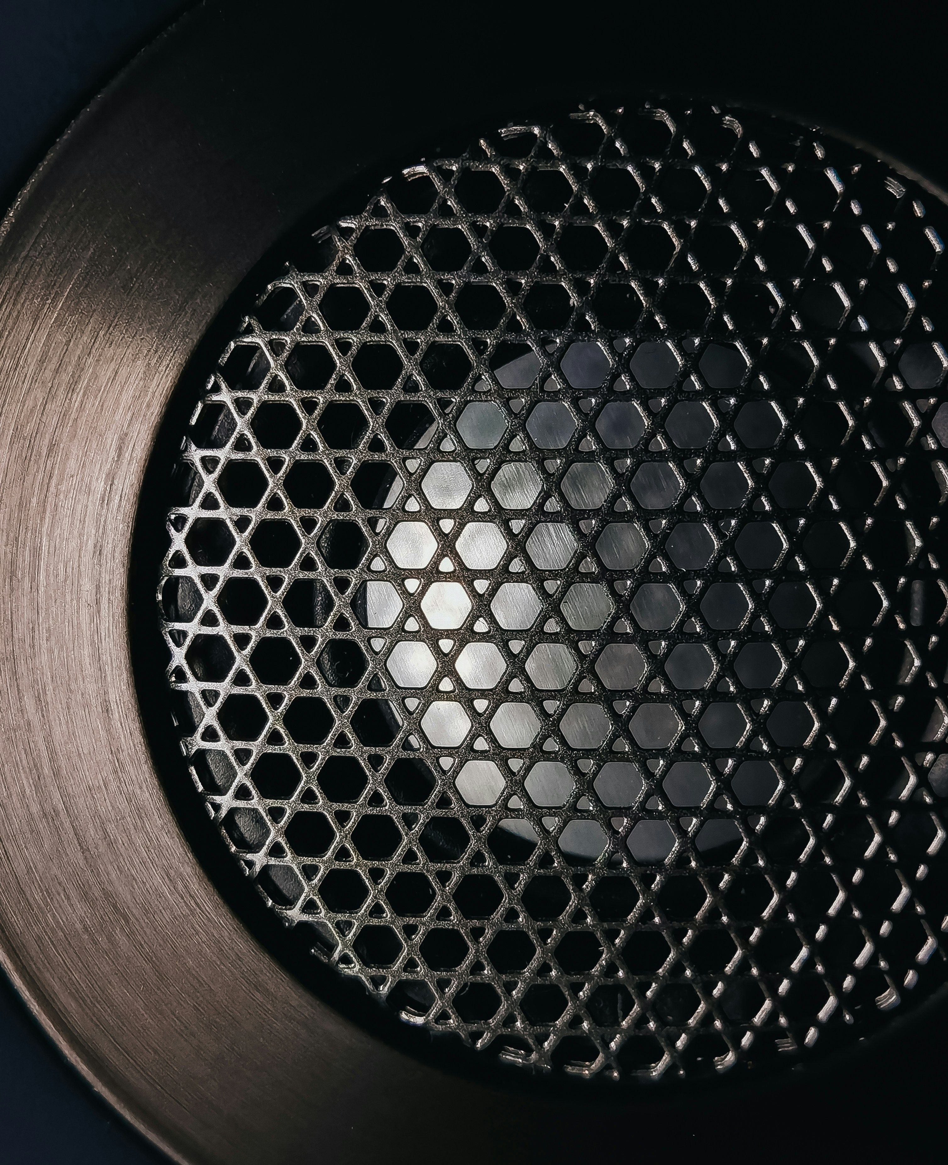 Close up of a speaker with a cross-lattice cover and wide metal rim