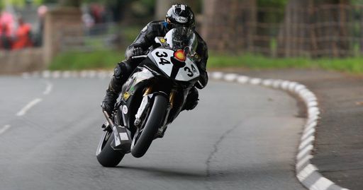 Dynamic shot of a motorcyclist speeding through the Isle of Man TT course.