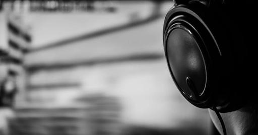 Black and white image of a person listening with headphones, conveying focus and immersion.