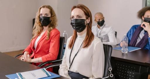 Diverse group of professionals in masks attending a business conference indoors.