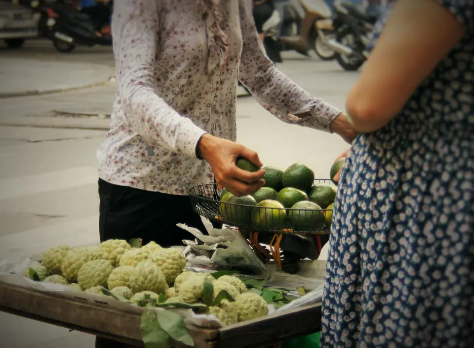 A stallholder weighing fruit at a market stall