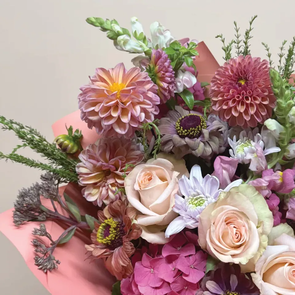 A pink bouquet of dahlias, roses, and other flowers