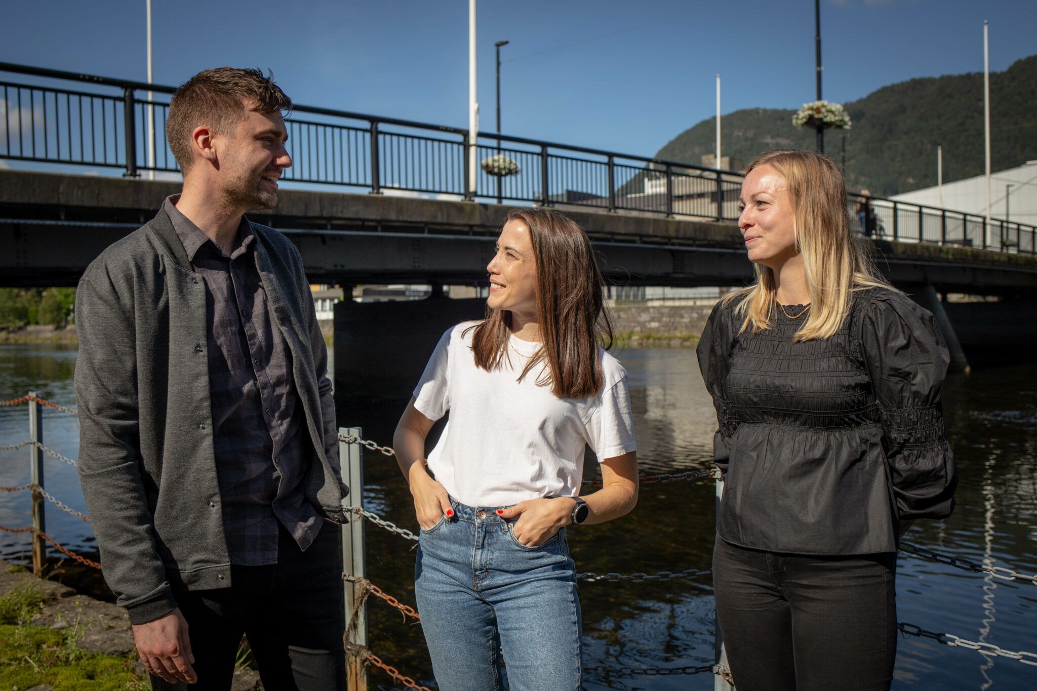 Tre glade kollegaer står ved bru