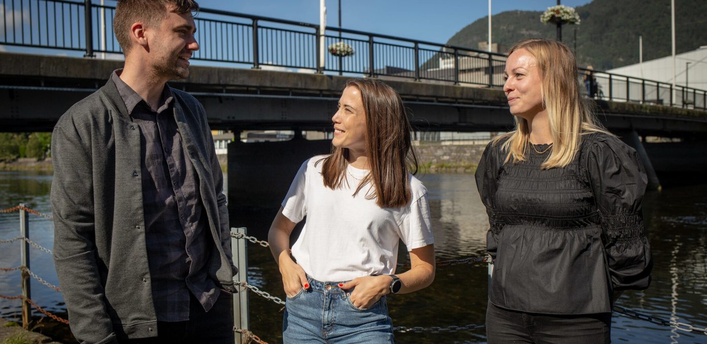 Tre glade kollegaer står ved bru