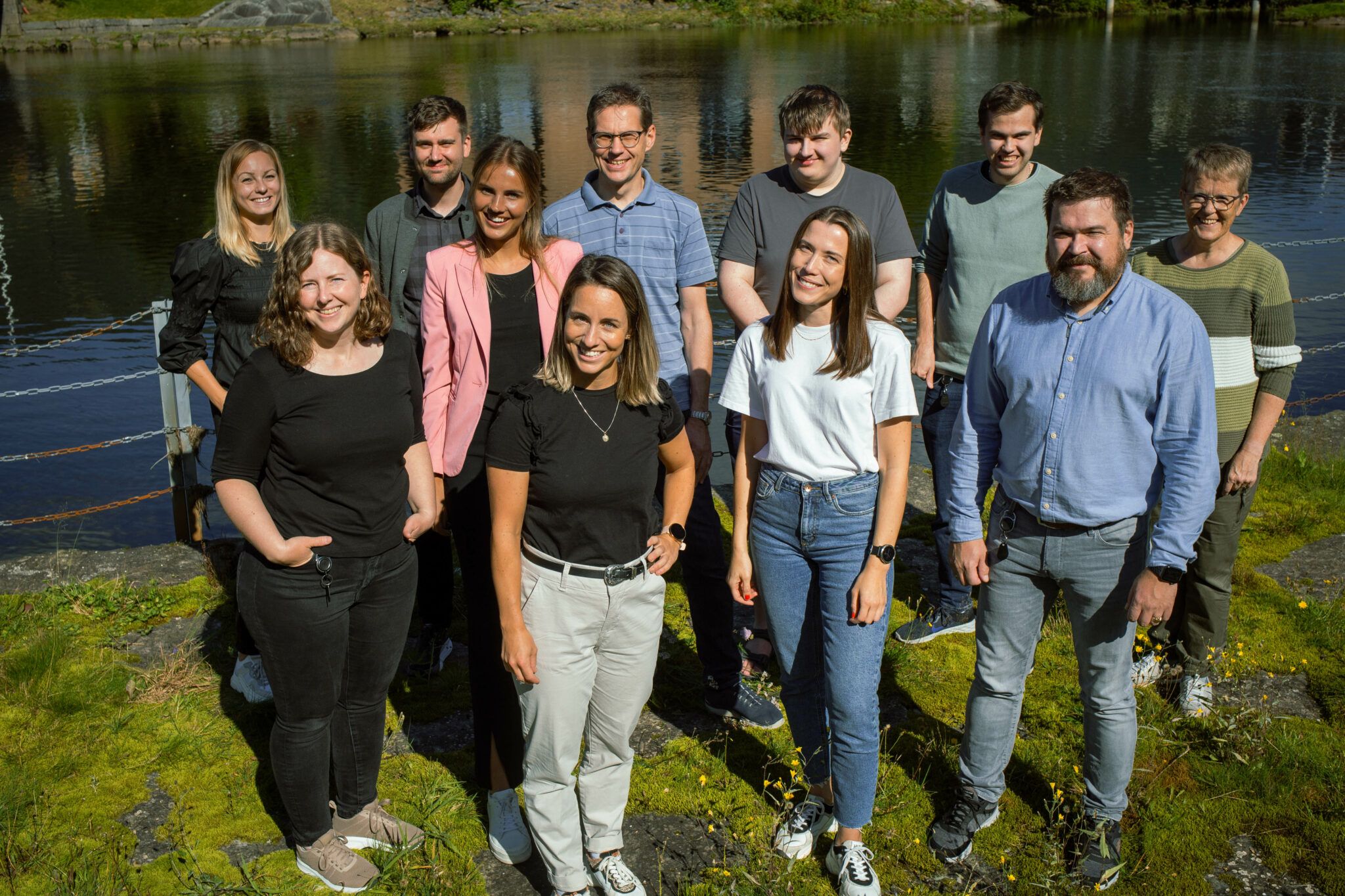 ti kollegaer smiler til kamera ved elvebredden i Førde.