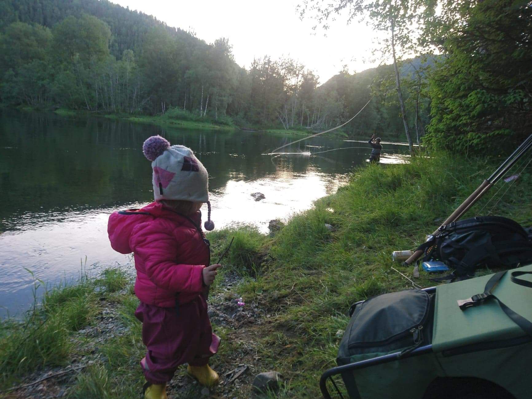 Et barn som ser på faren fiske i elva