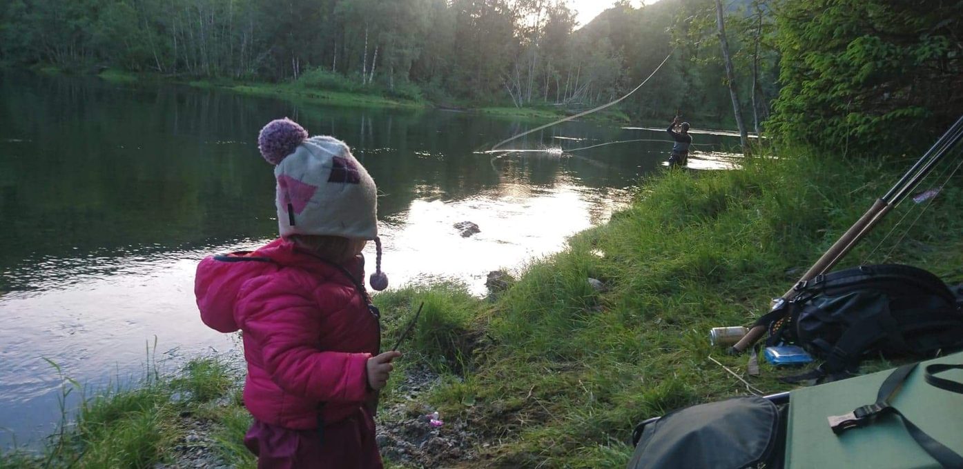 Et barn som ser på faren fiske i elva
