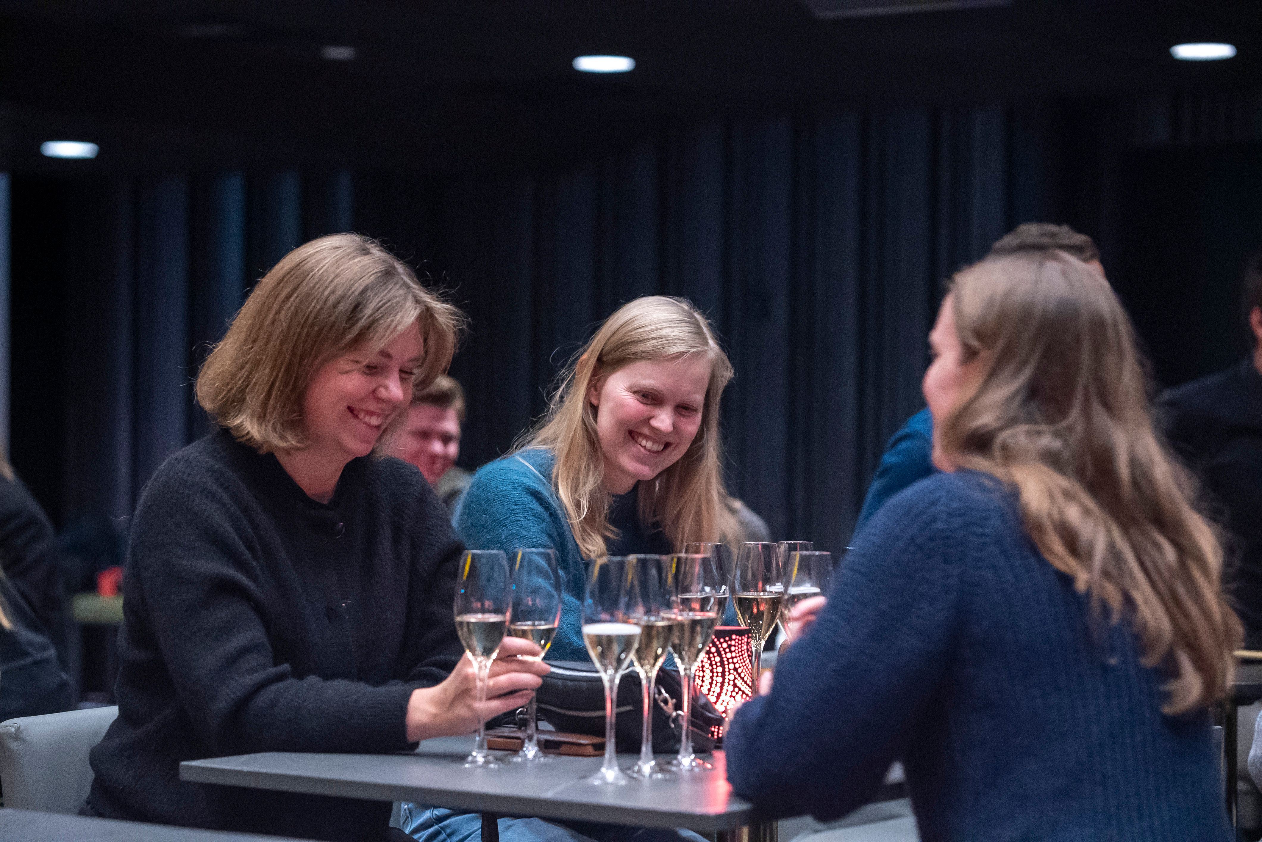 Tre kvinner ler på arrangement