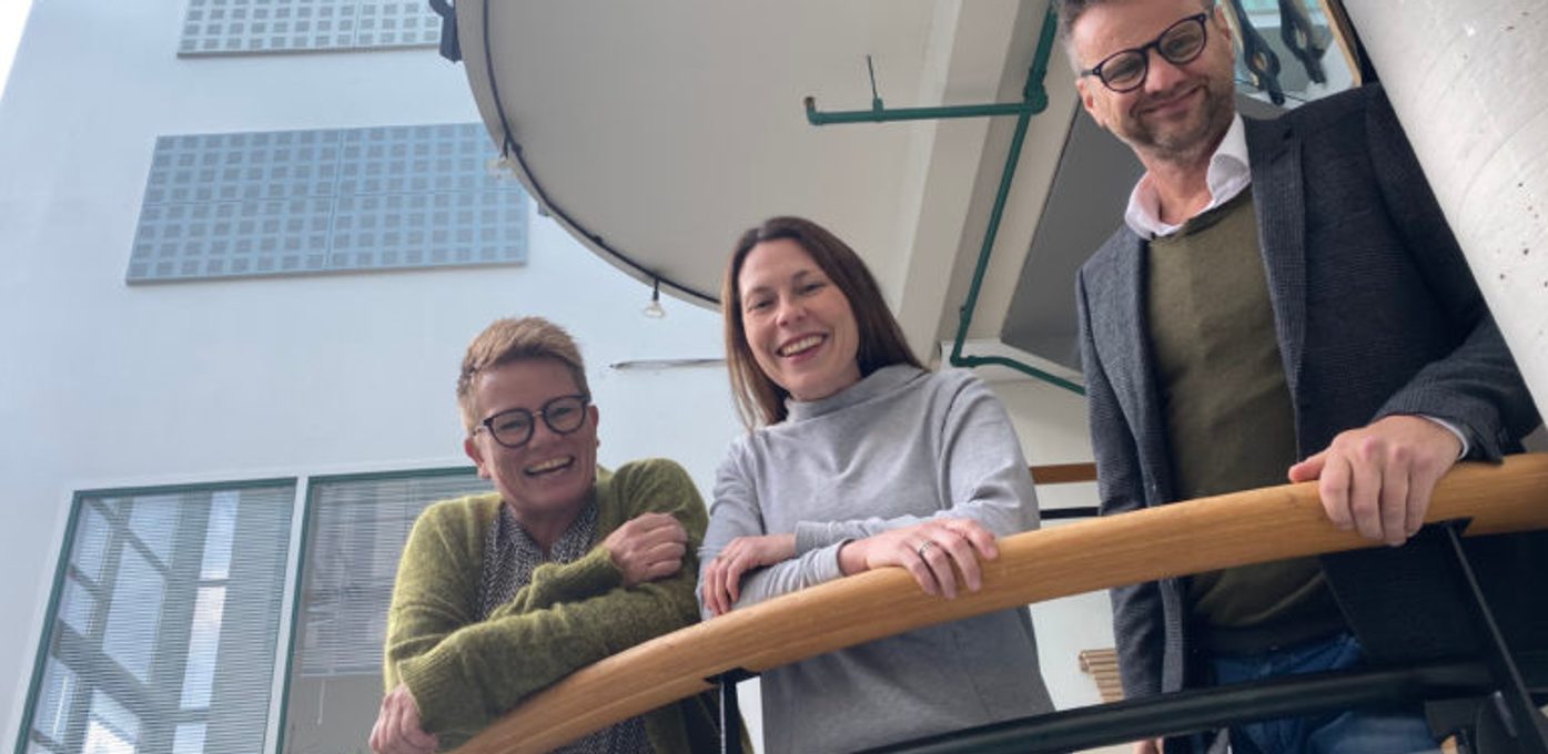 Tre personer som smiler til kamera