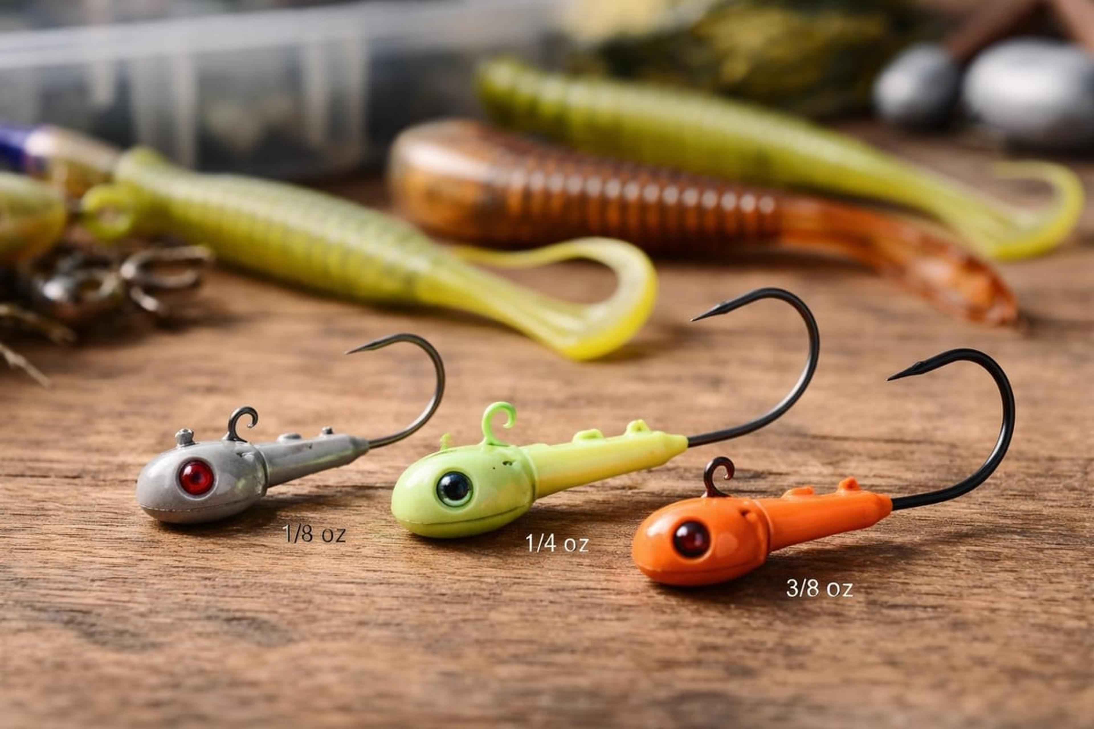 Three jig heads labelled 1/8 oz, 1/4 oz and 3/8 oz beside soft-plastic grubs and swimbaits