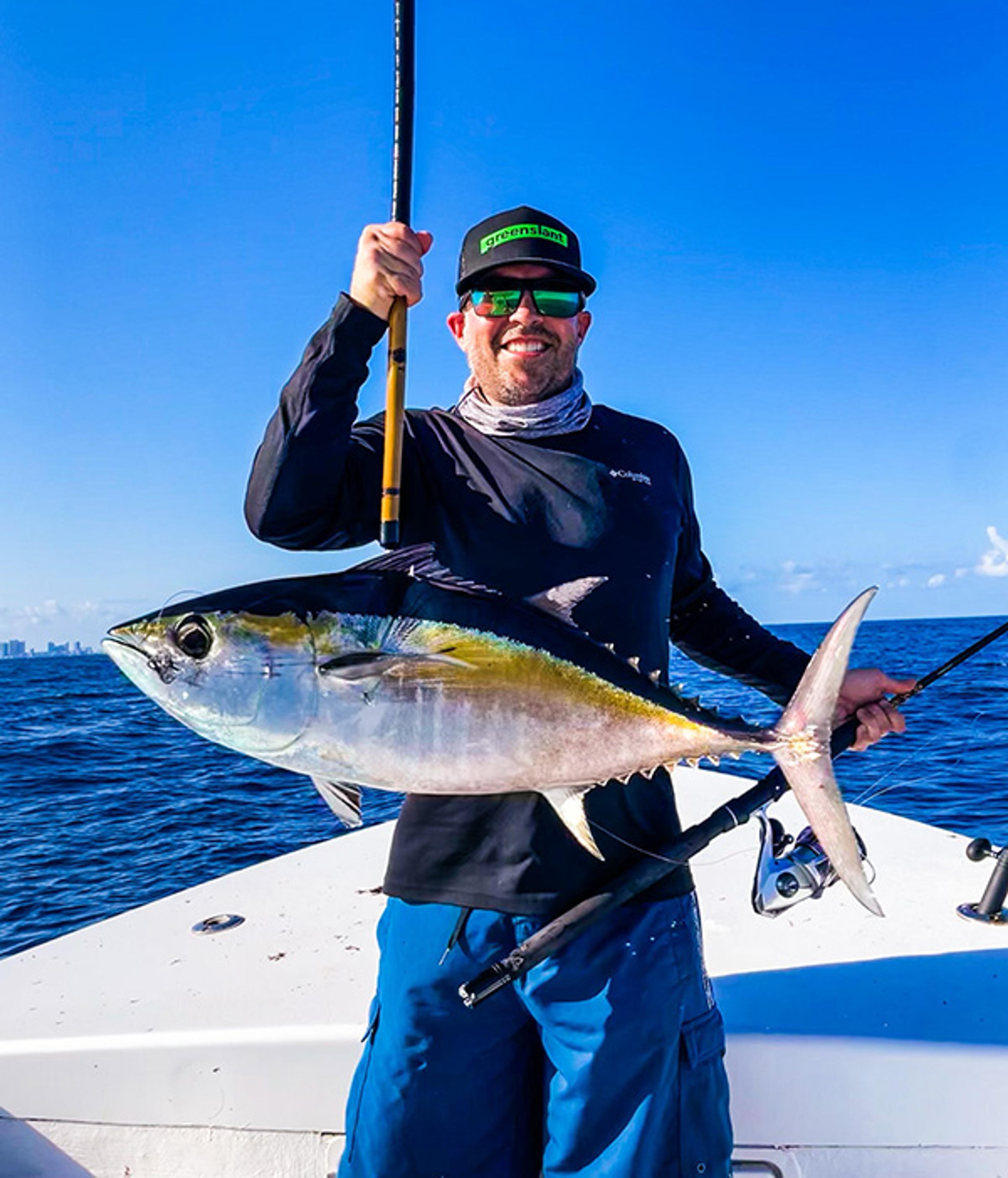 Matthew Howe holding a blackfin tuna on a boat offshore