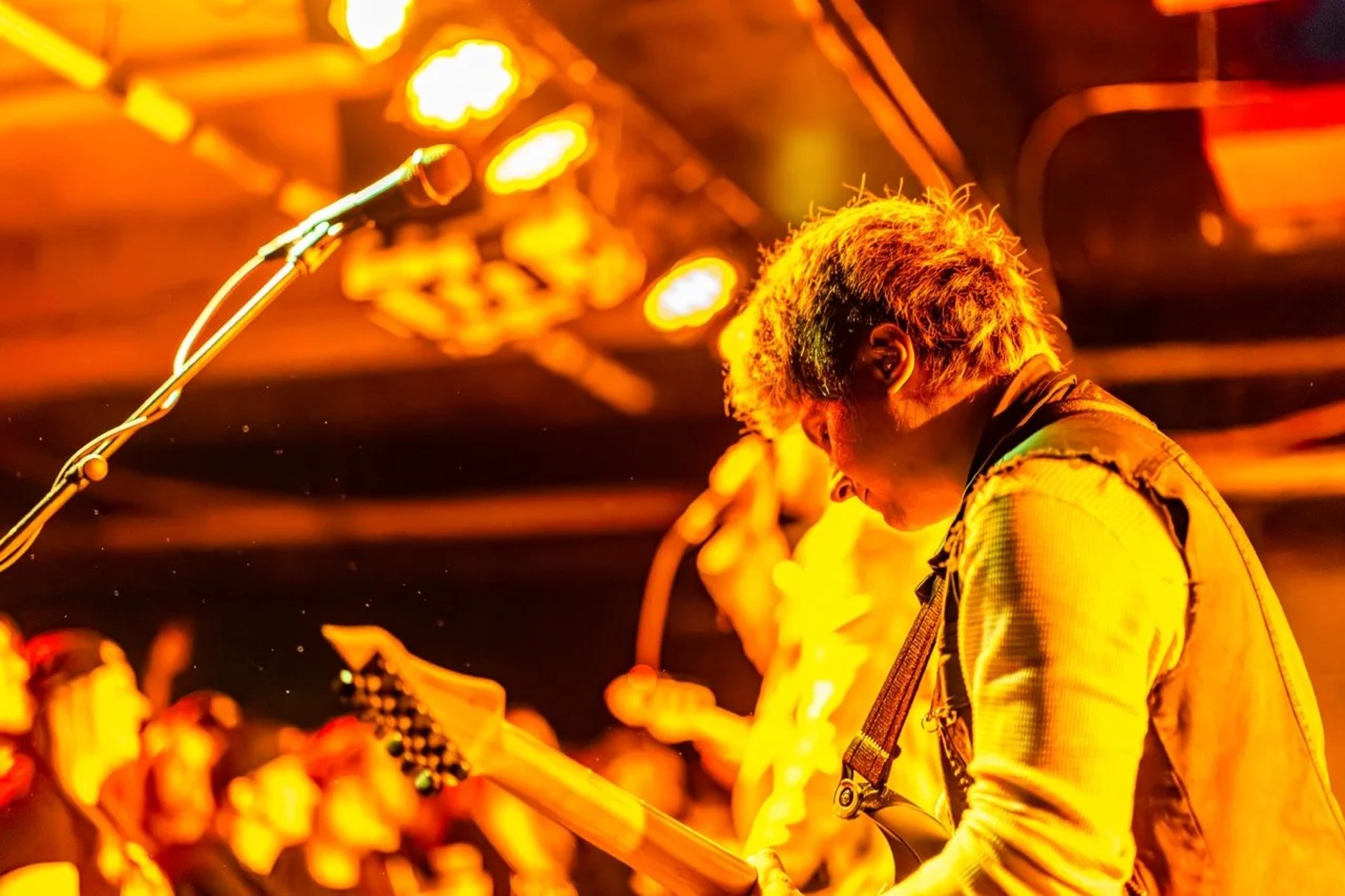 A guitarist performs on stage under warm orange stage lighting, singing into a microphone with intensity at Empire Live Underground.