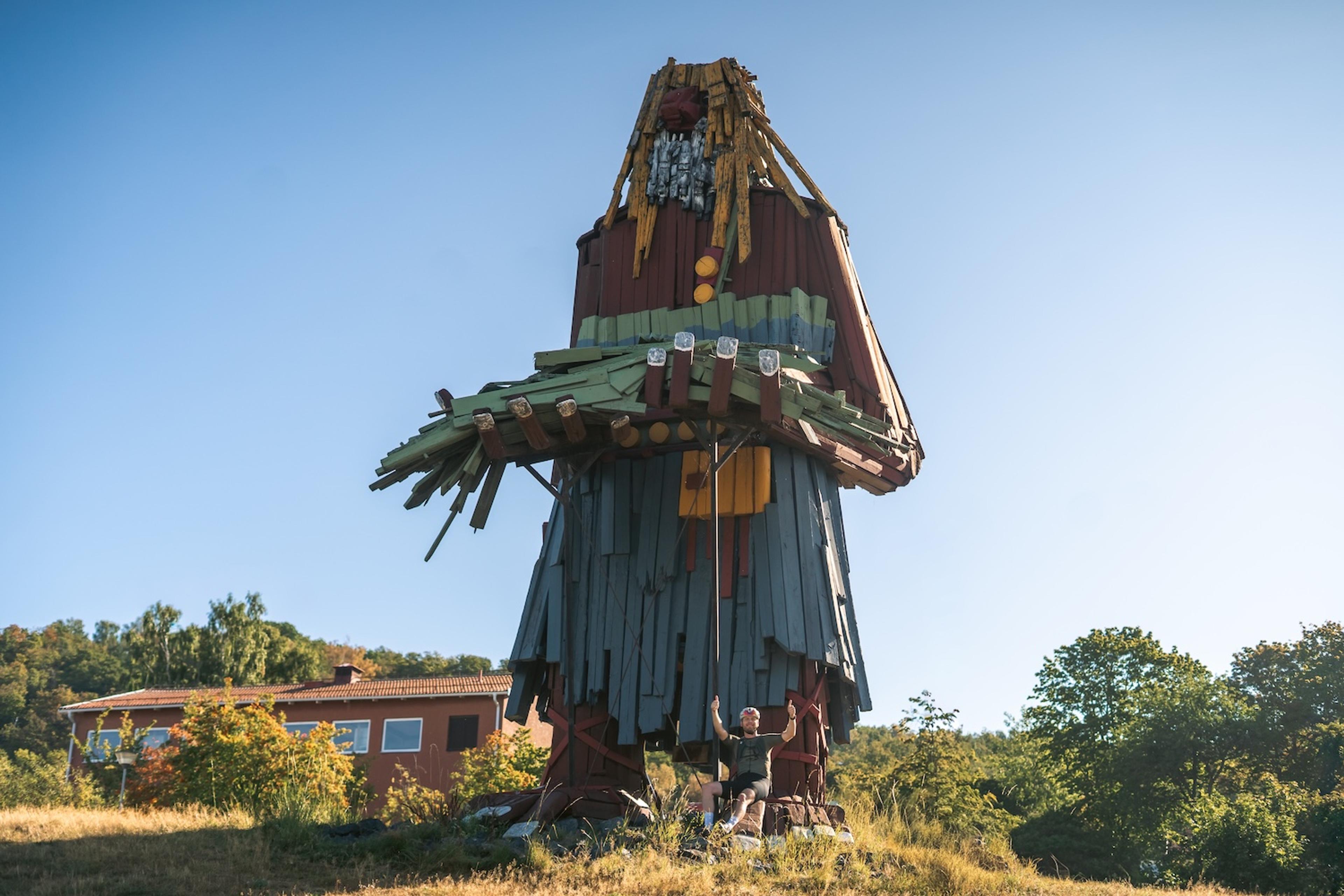 Giant colorful wooden troll with a person standing at its base.