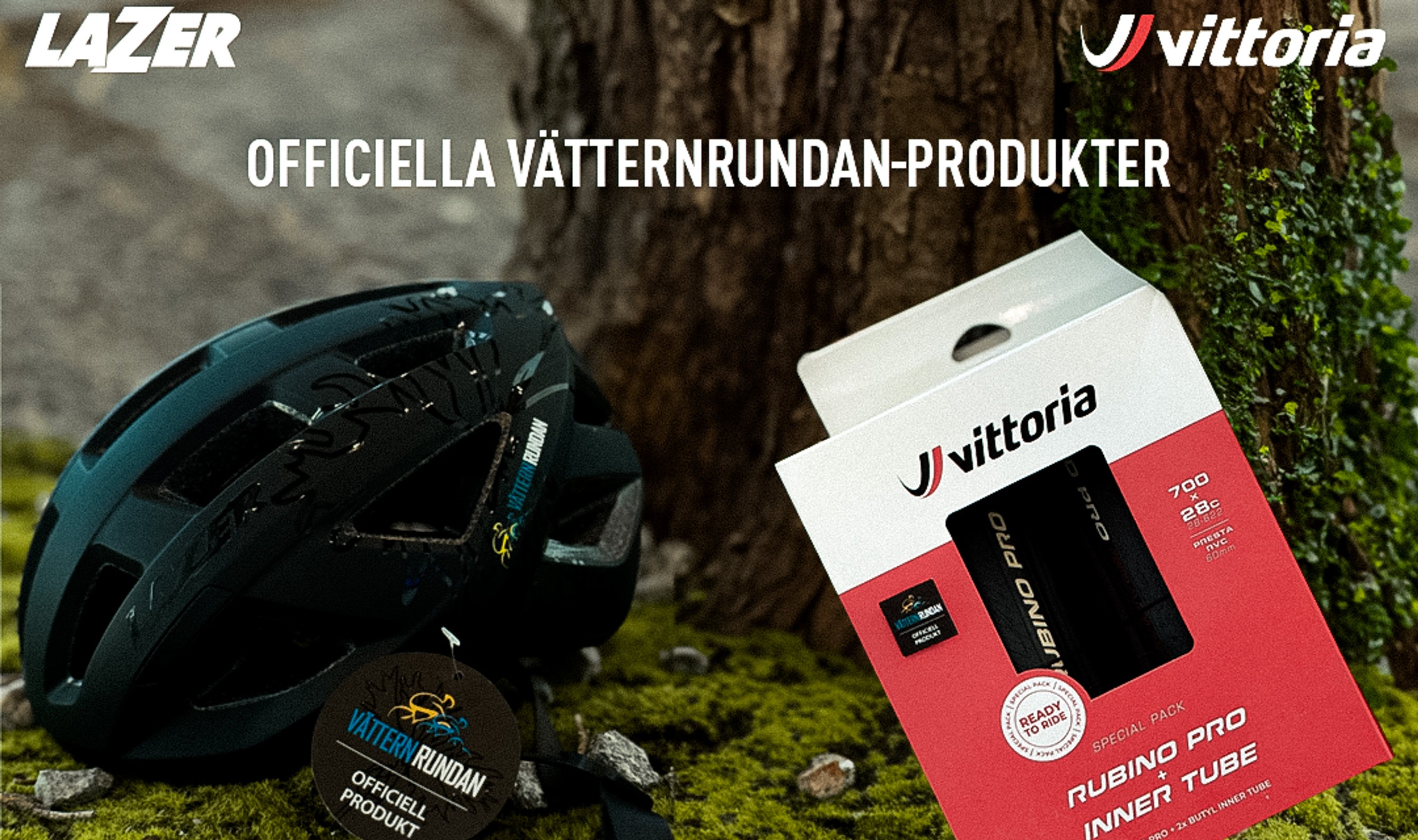 A black Lazer bike helmet and a Vittoria Rubino Pro inner tube box, both Vätternrundan branded, on moss near a tree.