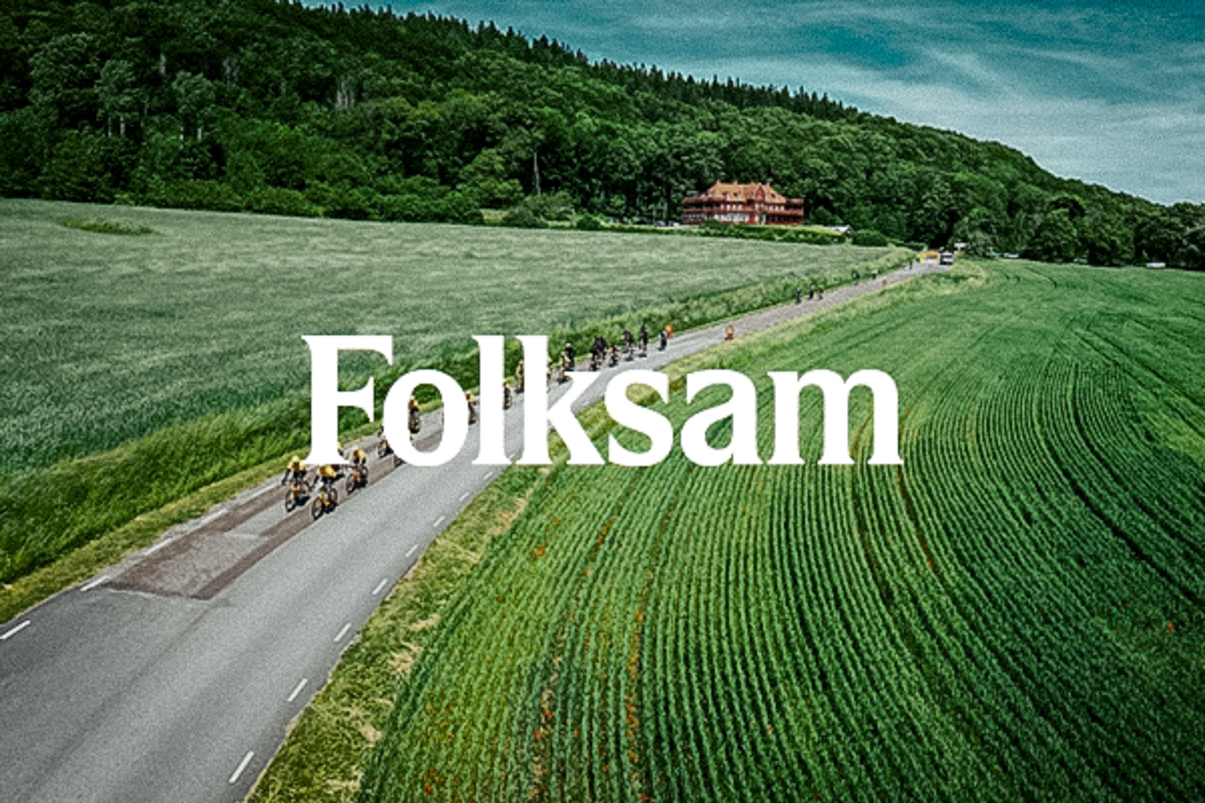 Aerial view of cyclists on a road winding through green fields with a forested hill and building in the background, with 'Folksam' text overlaid.