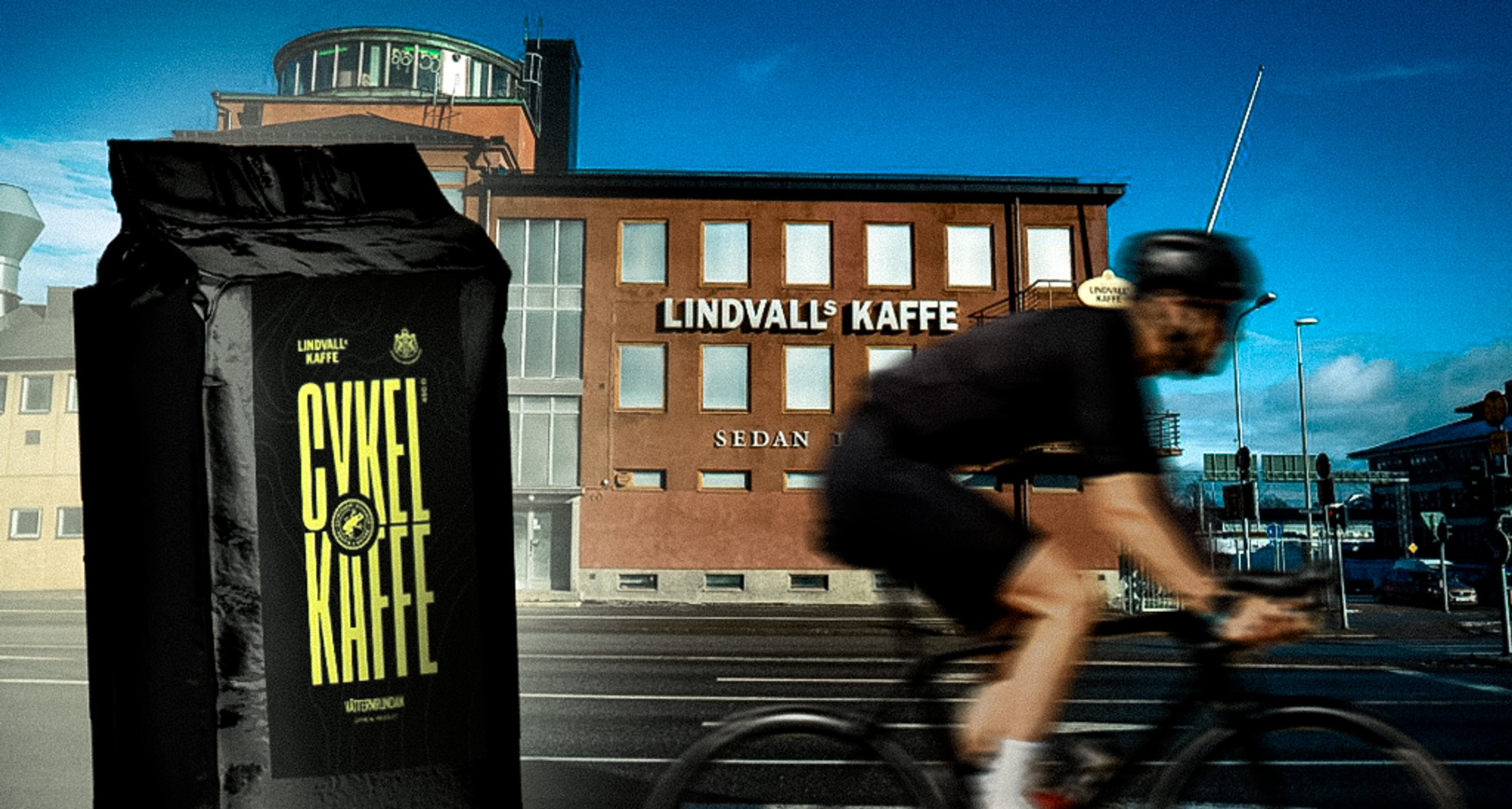 A black bag of Lindvall's Cykel Kaffe in front of a blurred cyclist and a building labeled Lindvall's Kaffe.