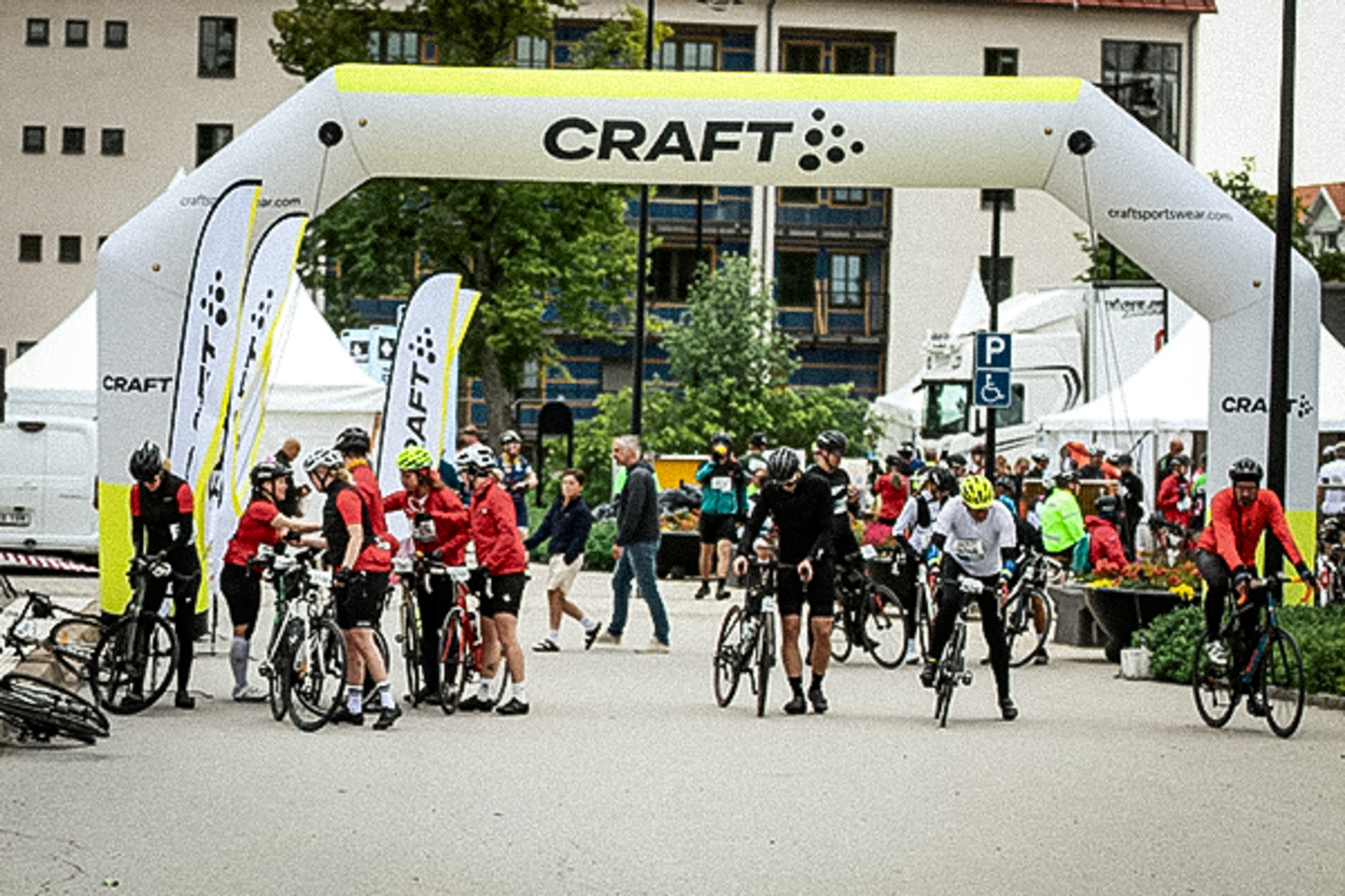 Cyclists and bikes gathered under a "CRAFT" archway at an outdoor event.