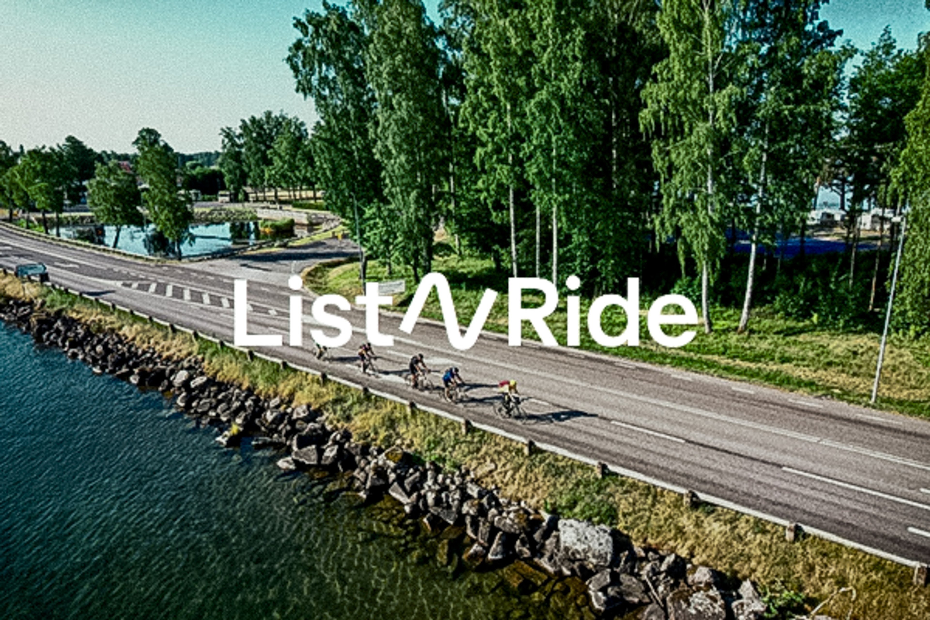 Aerial view of cyclists riding on a road next to a lake and trees, with 'List^Ride' text.