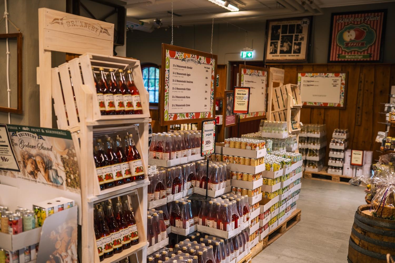 A well-stocked shop featuring bottled beverages displayed in wooden crates and on pallets.