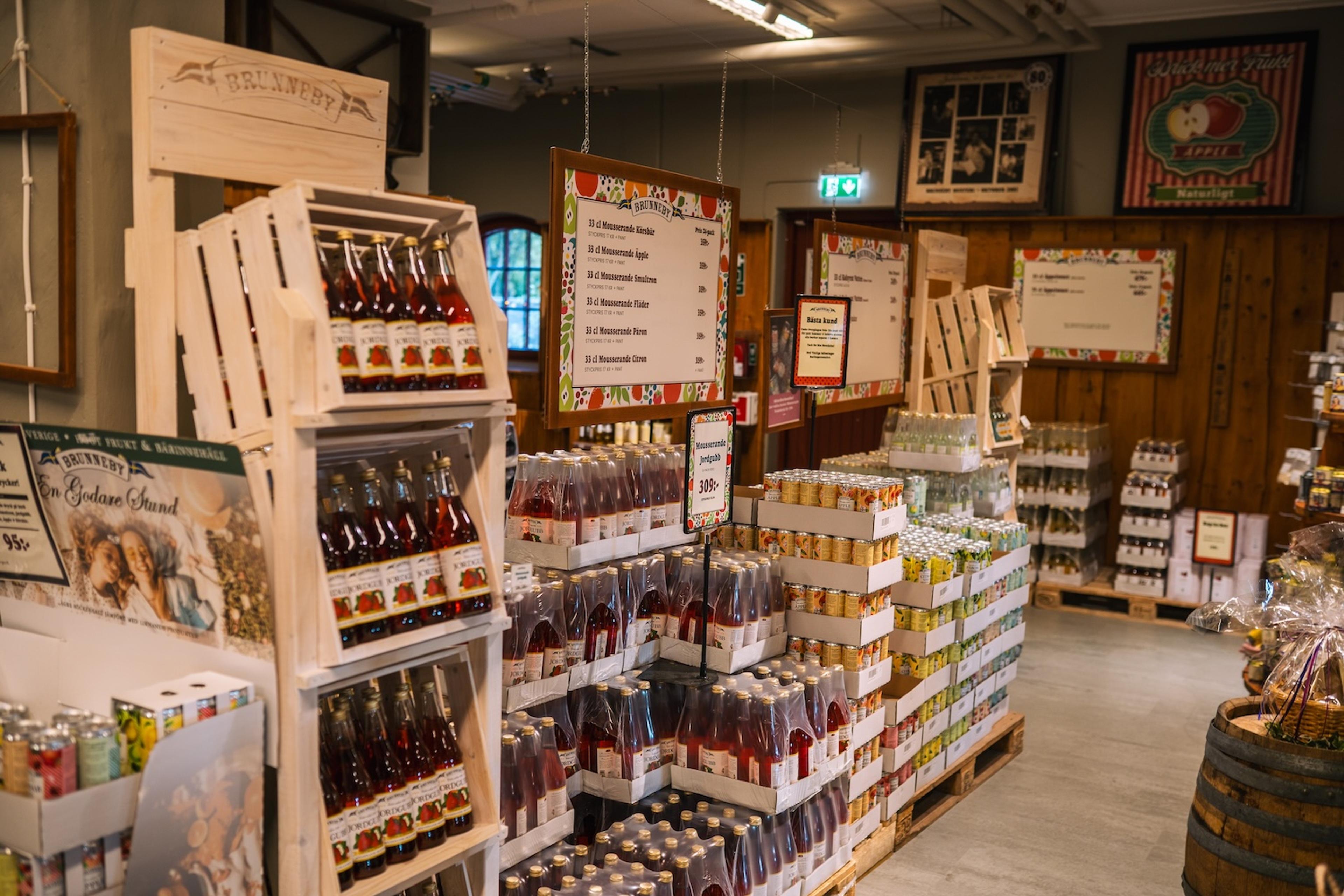 A well-stocked shop featuring bottled beverages displayed in wooden crates and on pallets.