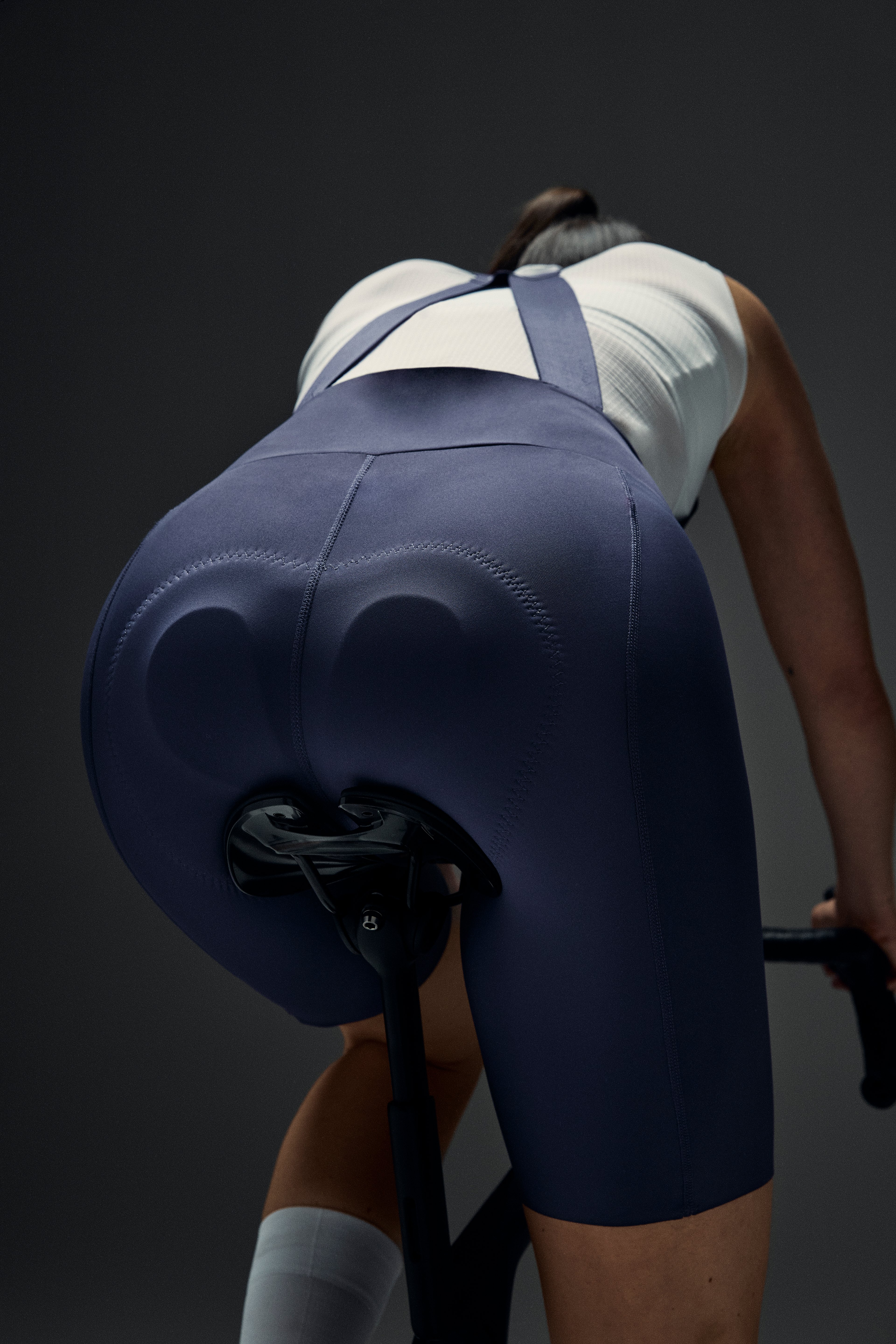 Rear view of a cyclist in navy bib shorts with prominent seat padding on a bike.
