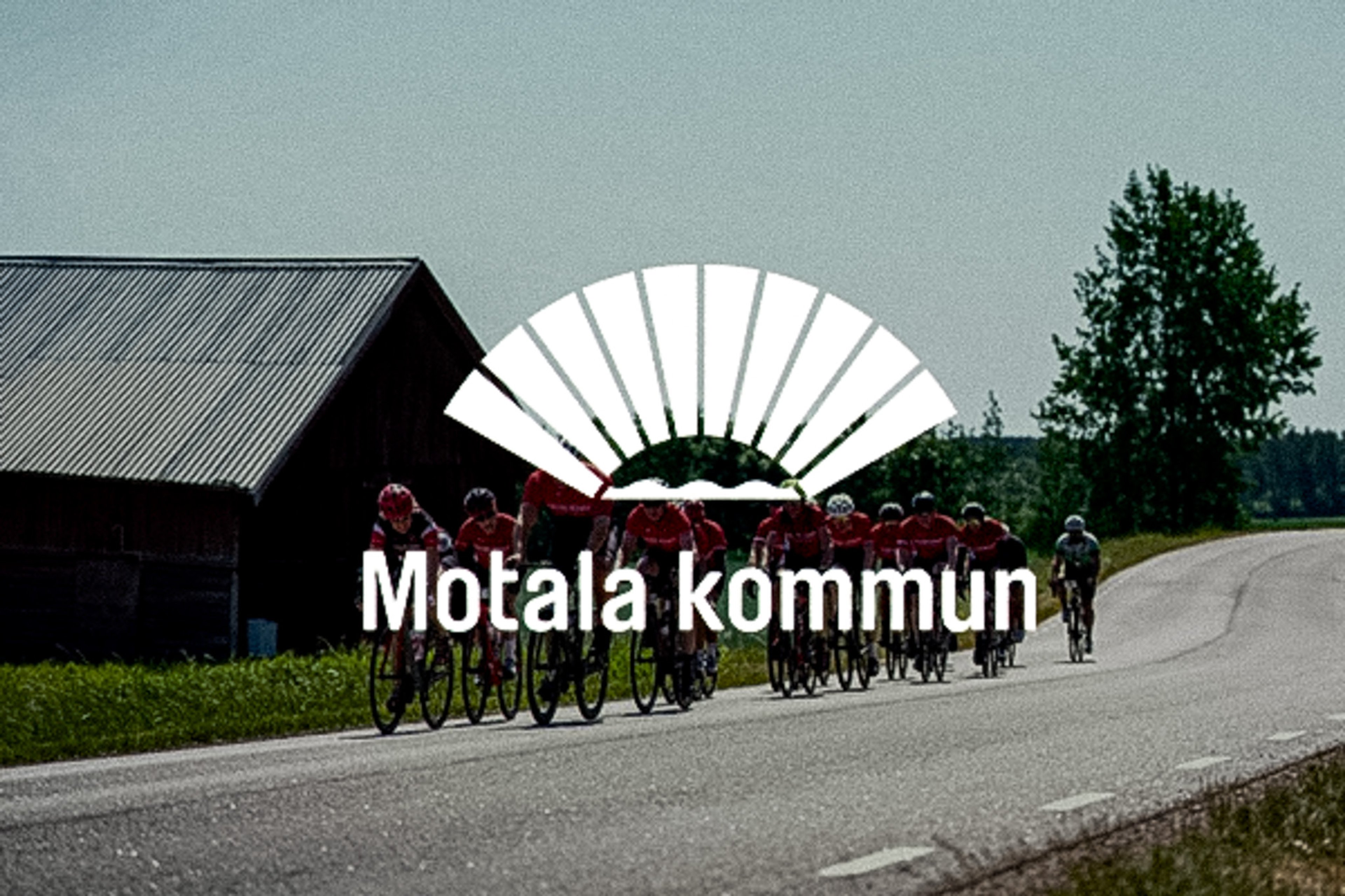A group of cyclists on a rural road with a barn and trees, overlaid with "Motala kommun" and a white fan-shaped logo.