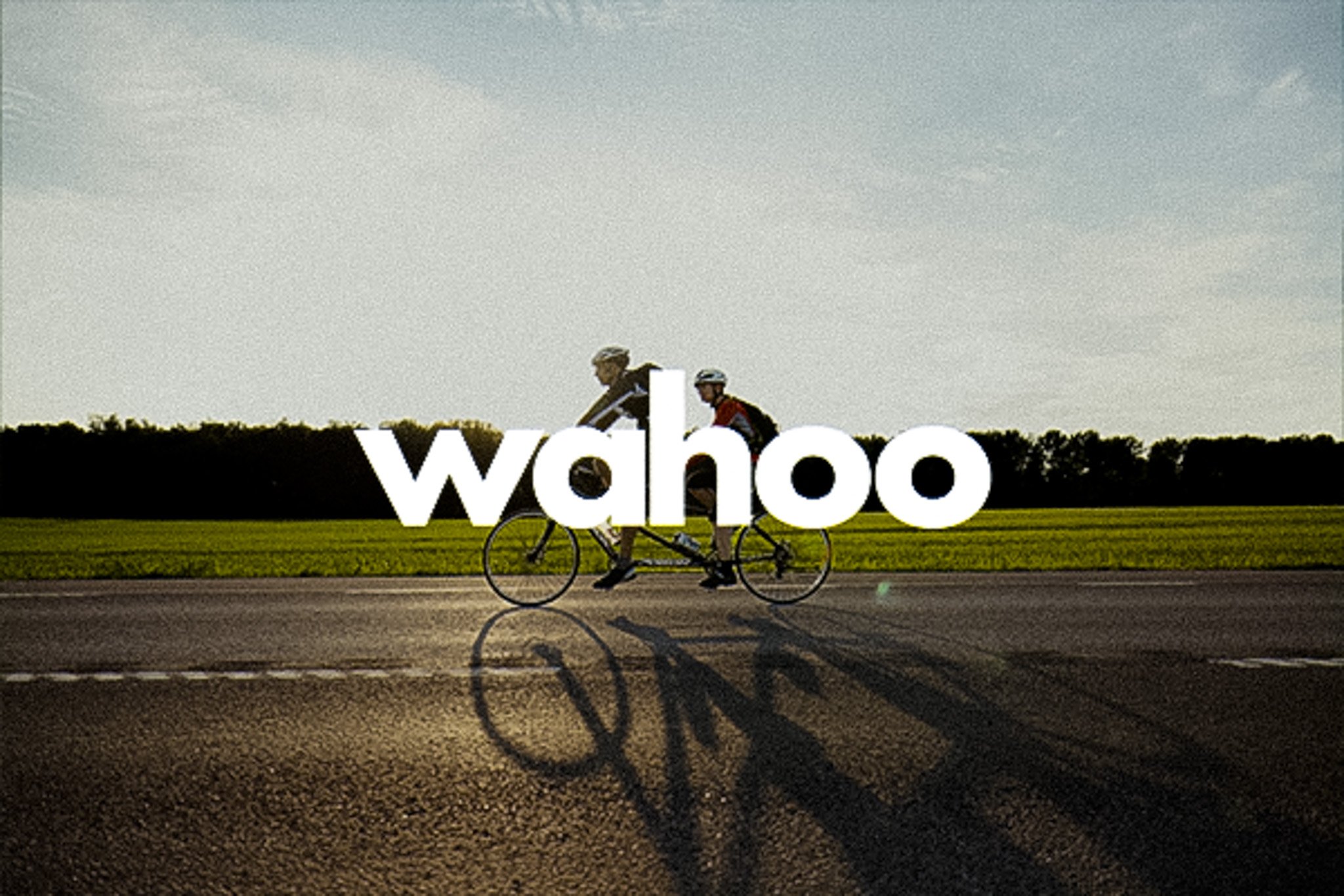 Wahoo logo superimposed over two cyclists riding on a road.
