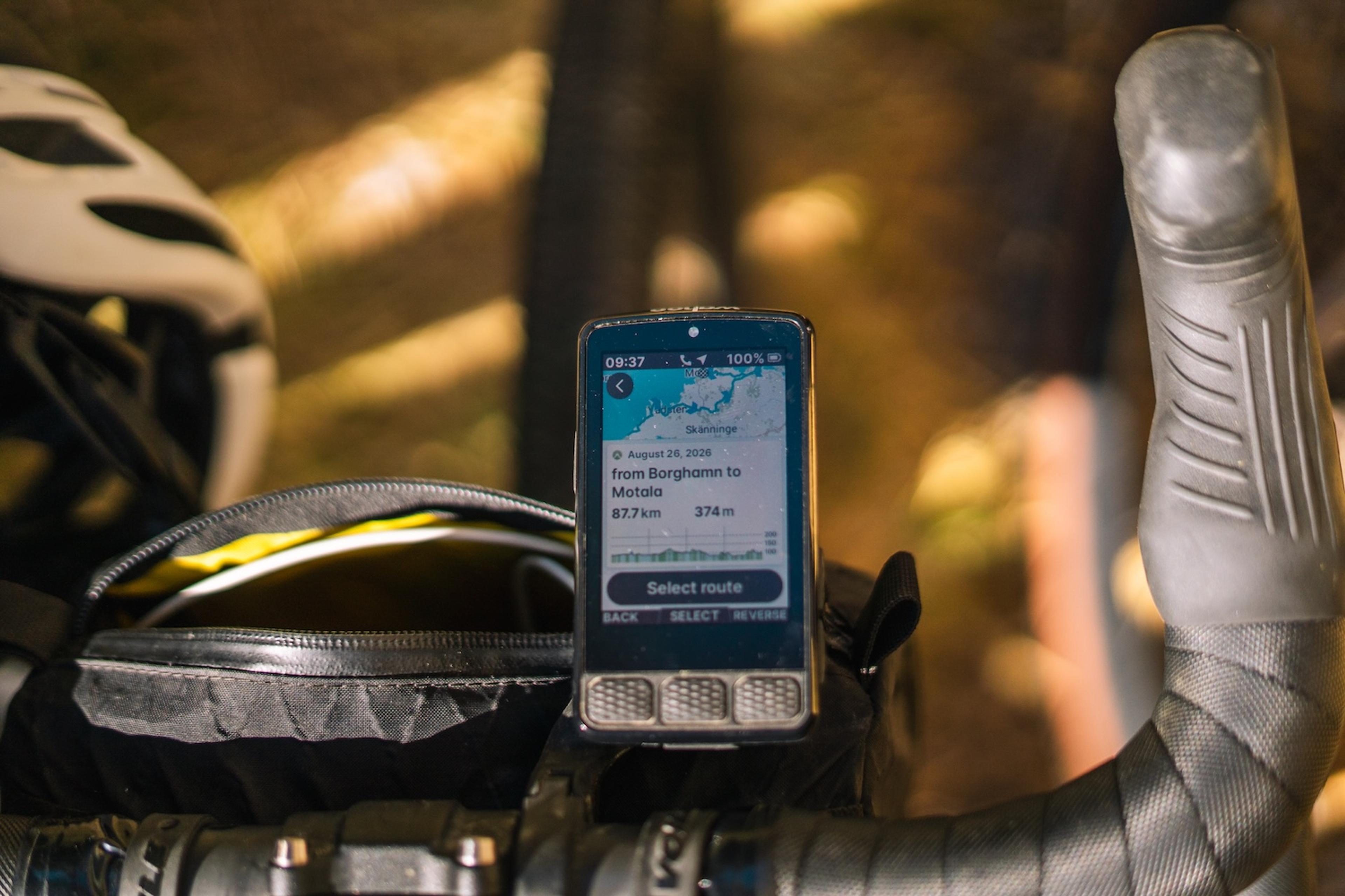 A smartphone mounted on bicycle handlebars displays a navigation map with route details.