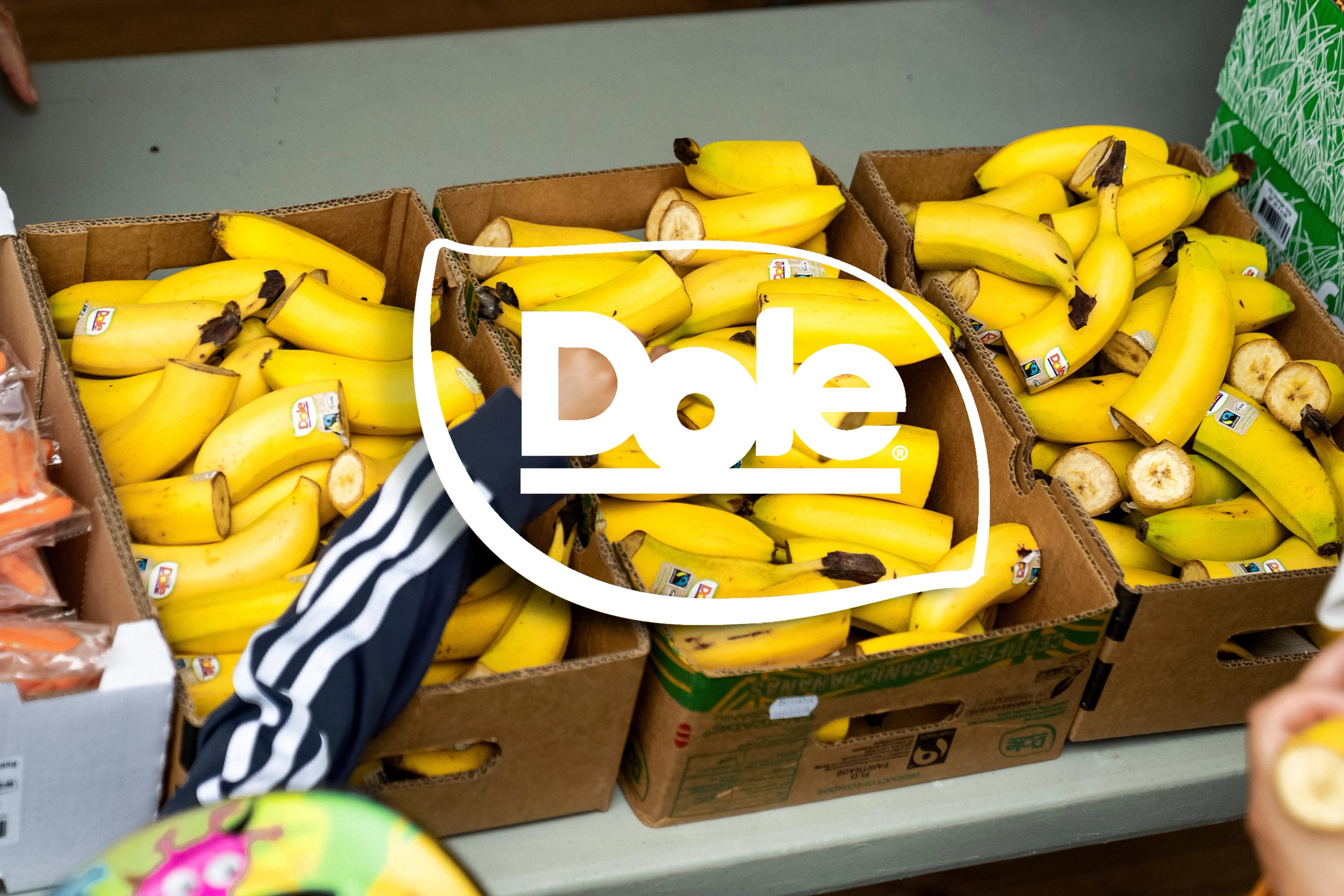 Dole logo over three boxes of ripe yellow bananas, some sliced.
