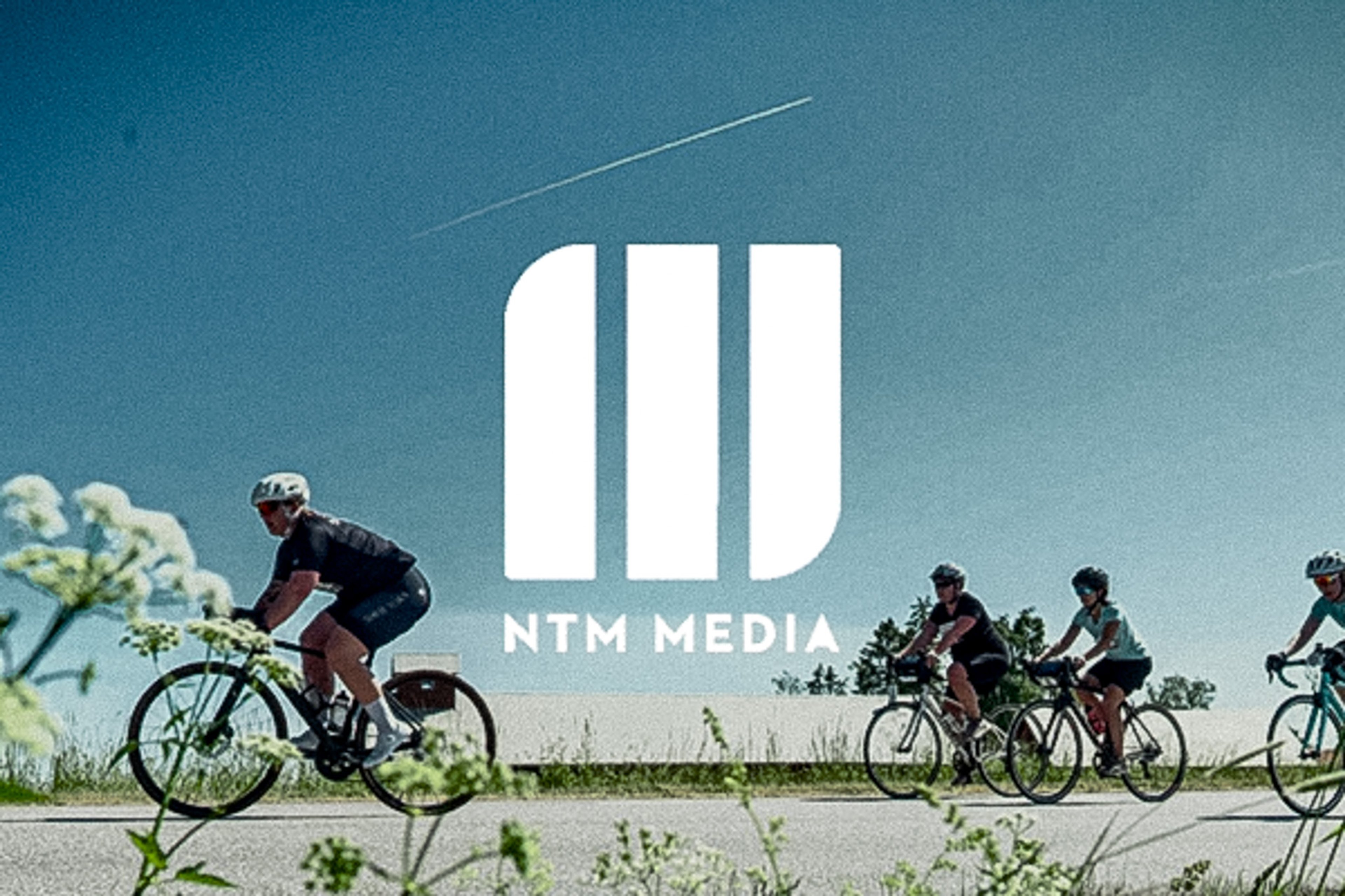 White NTM Media logo above cyclists on a road.