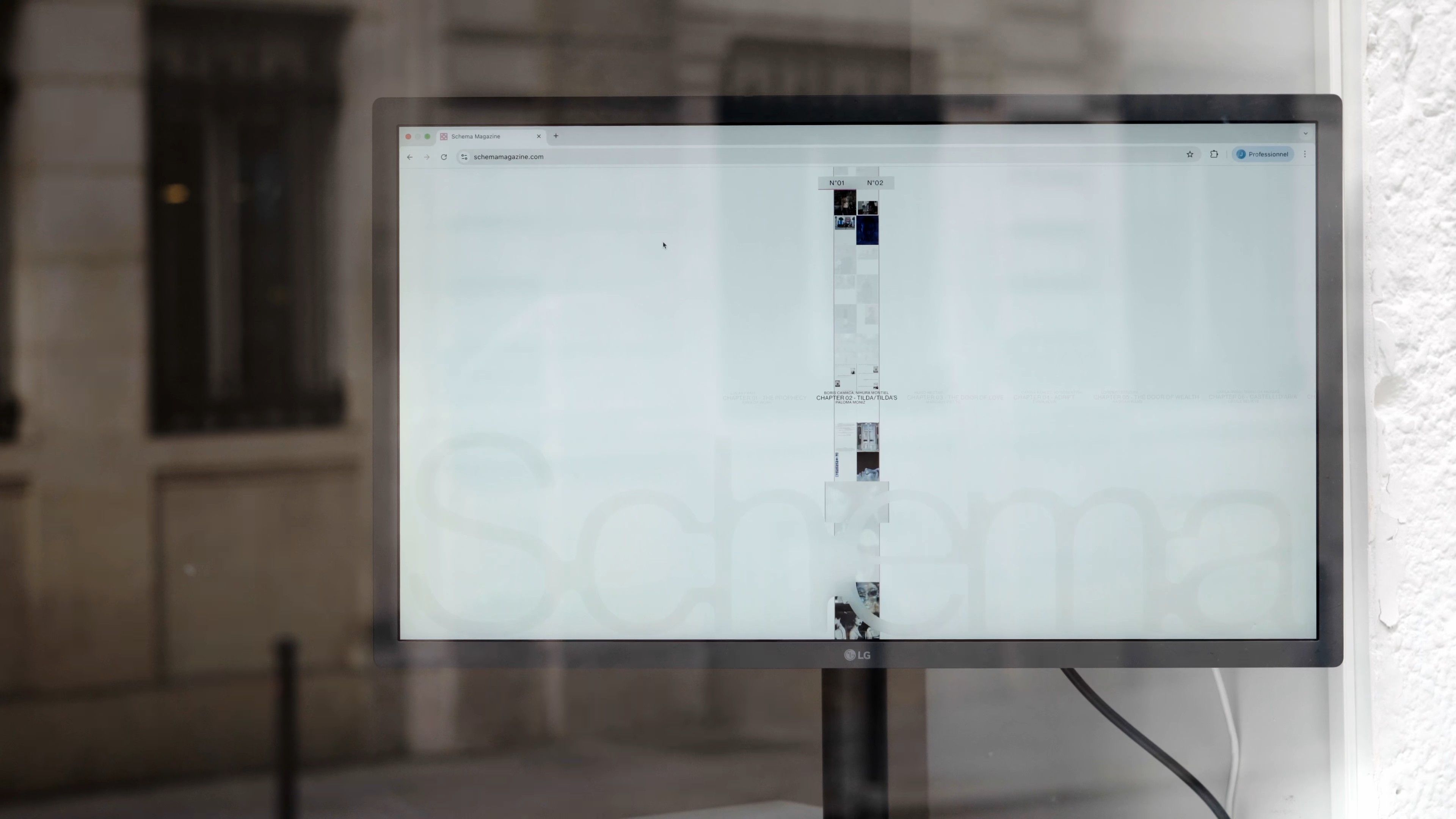Wider view of the same Schema Magazine shop-window monitor, the desktop chemin-de-fer layout visible behind the frosted “Schema” decal and the storefront’s glass reflections.